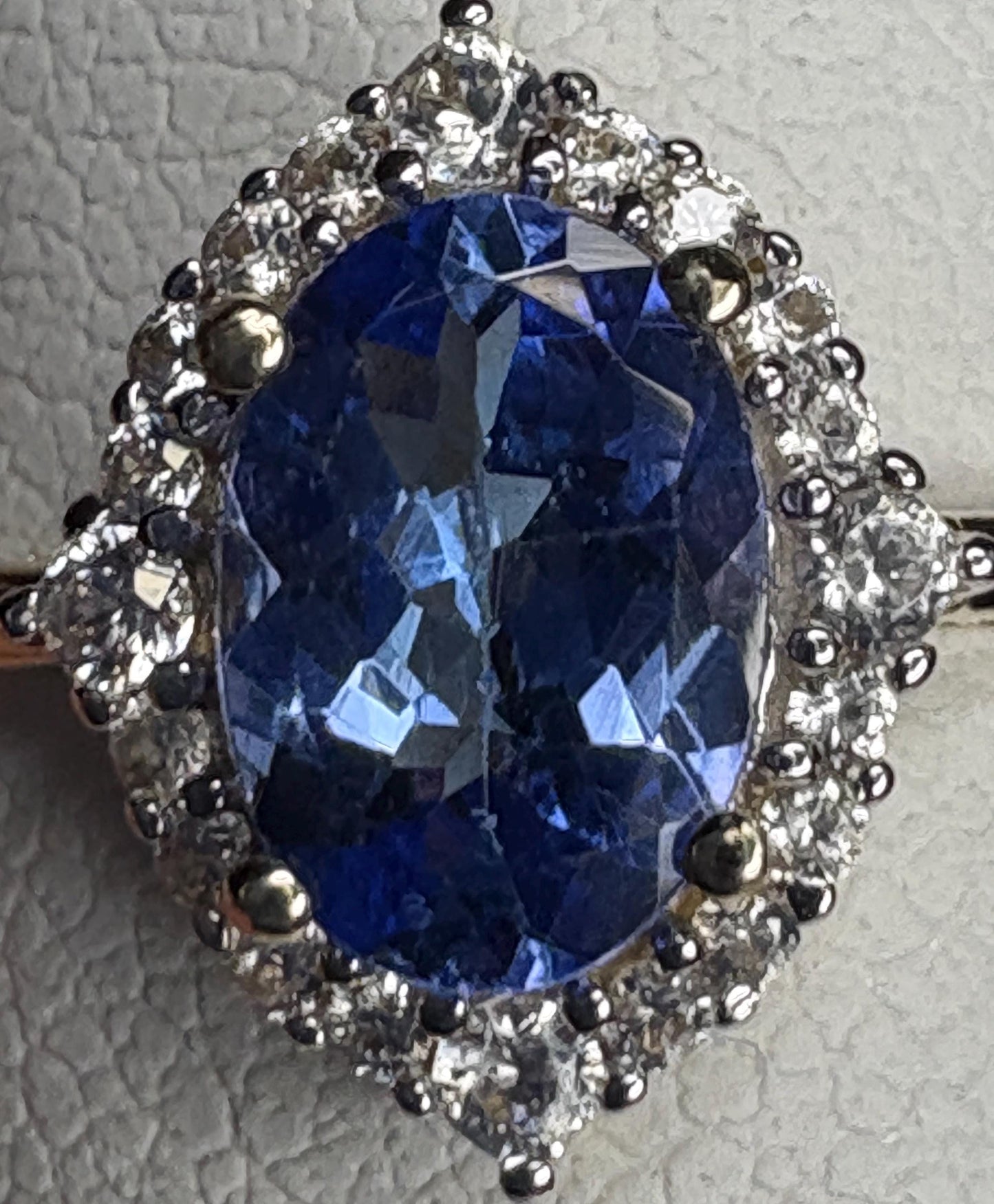 Oval tanzanite and white zircon halo ring in 9k gold.