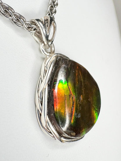 Sterling silver pendant necklace with a braided bezel holding a pear-shaped ammolite gemstone.