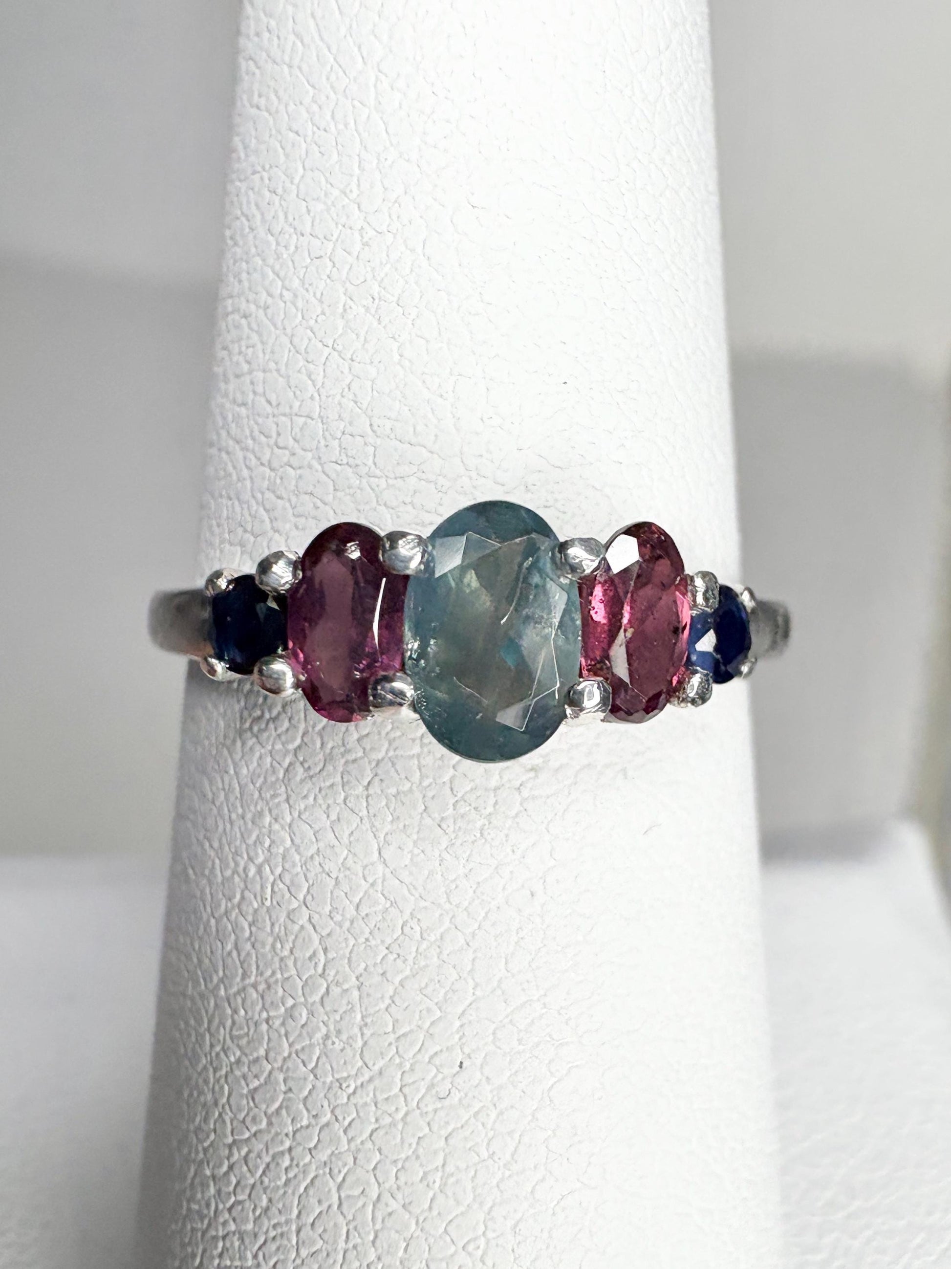 Sterling silver band ring with a central oval alexandrite and flanking rhodolite garnets and blue sapphires.