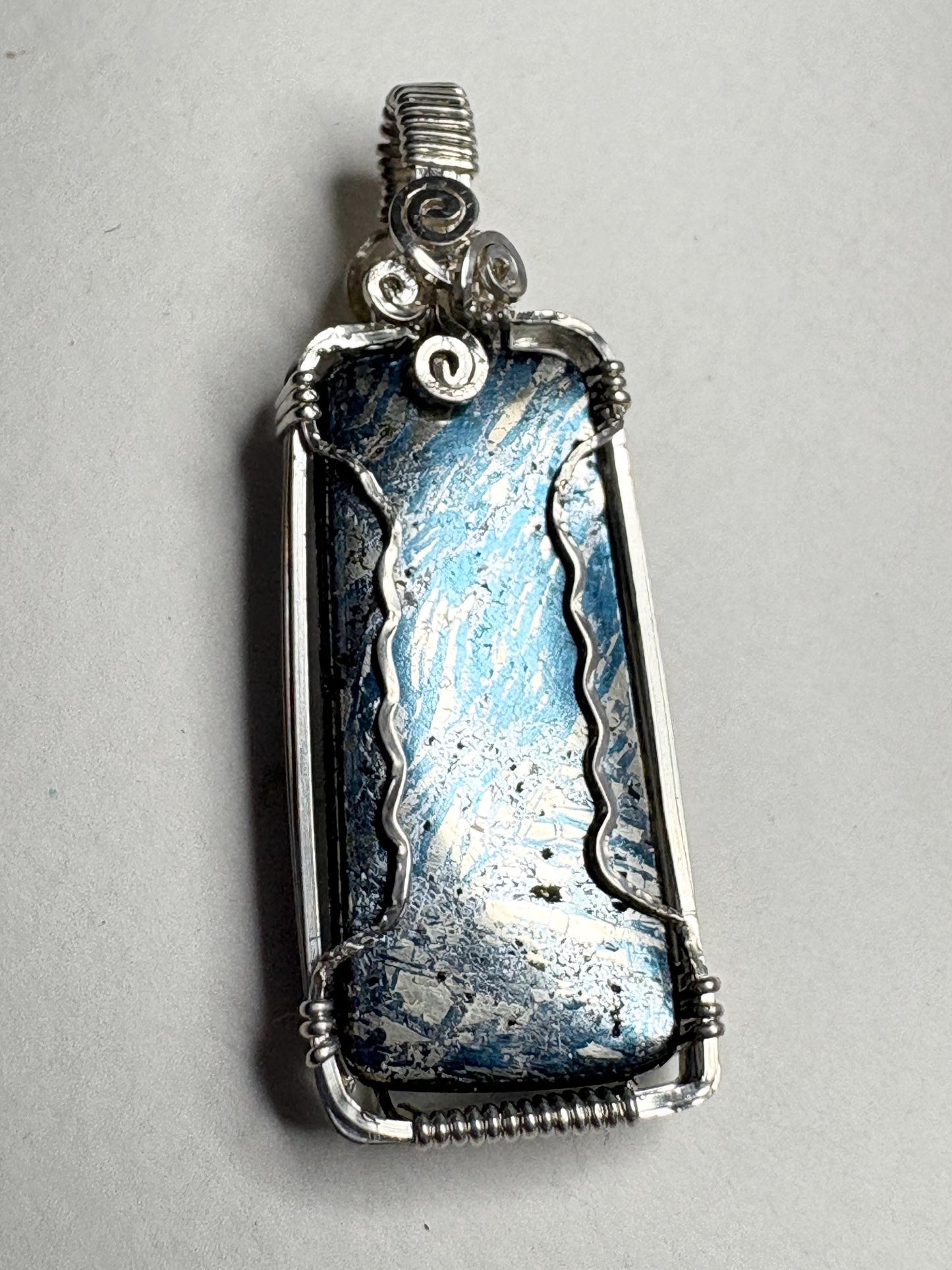Wire wrapped sterling silver pendant featuring a rectangular covellite stone with blue and silver metallic luster.