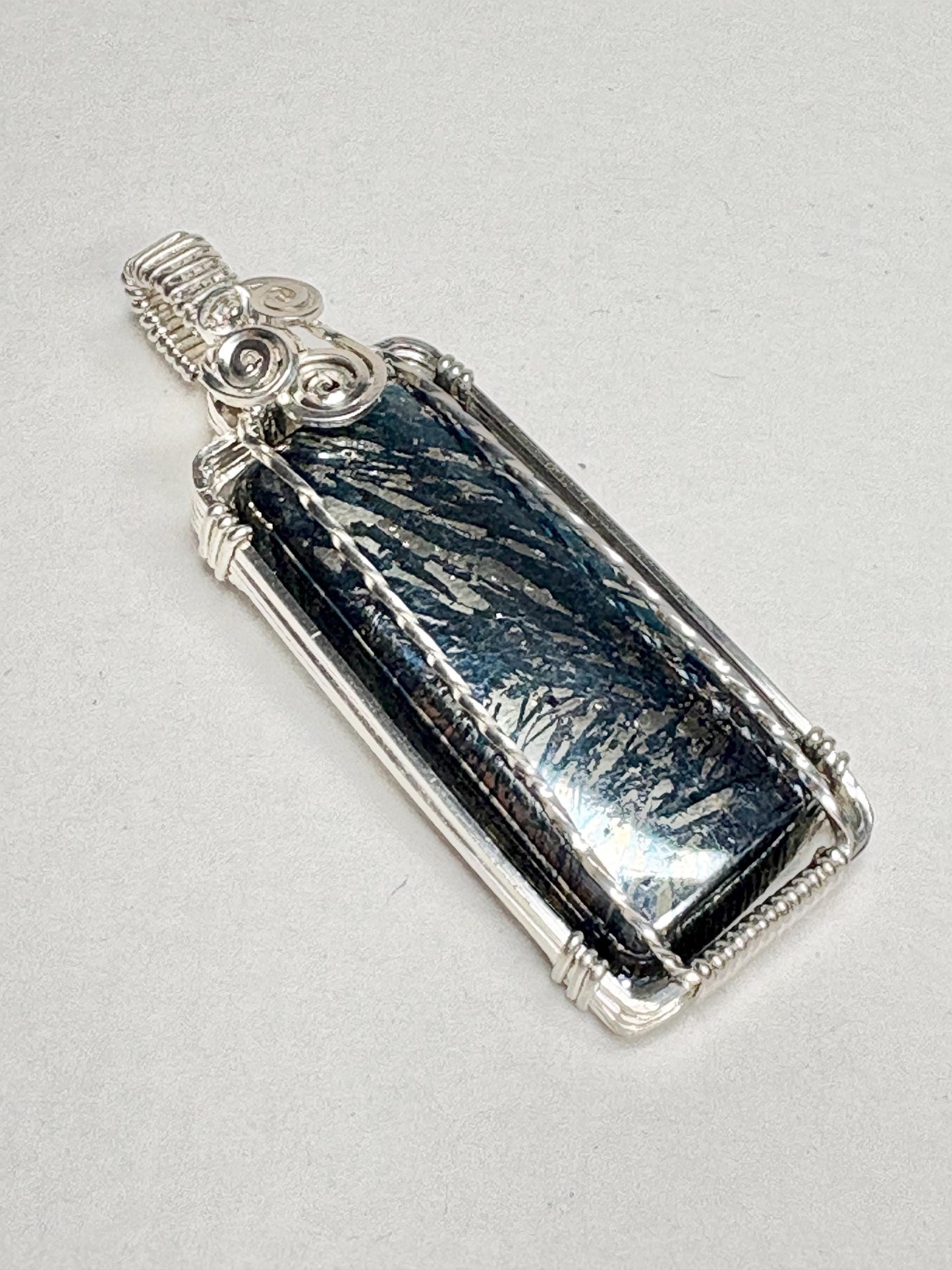 Sterling silver wire-wrapped pendant featuring a rectangular covellite stone with metallic blue and gold striations.