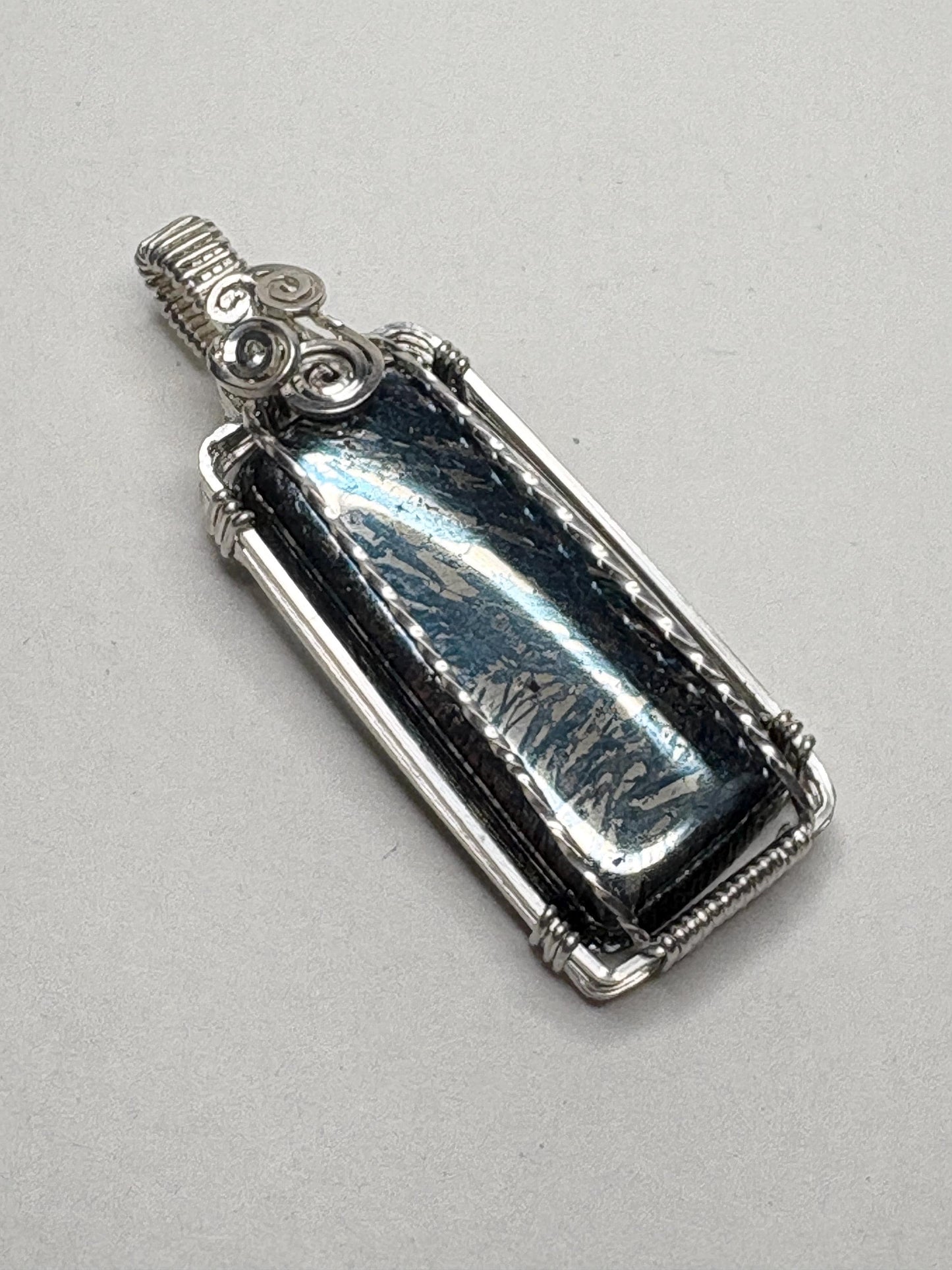 Sterling silver wire-wrapped pendant featuring a rectangular covellite stone with metallic blue and gold hues.