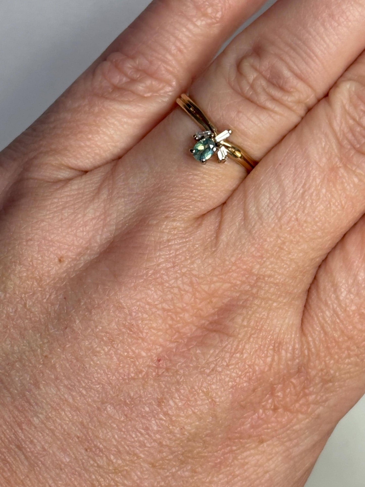 A 14k gold ring with an oval alexandrite and three baguette diamonds.