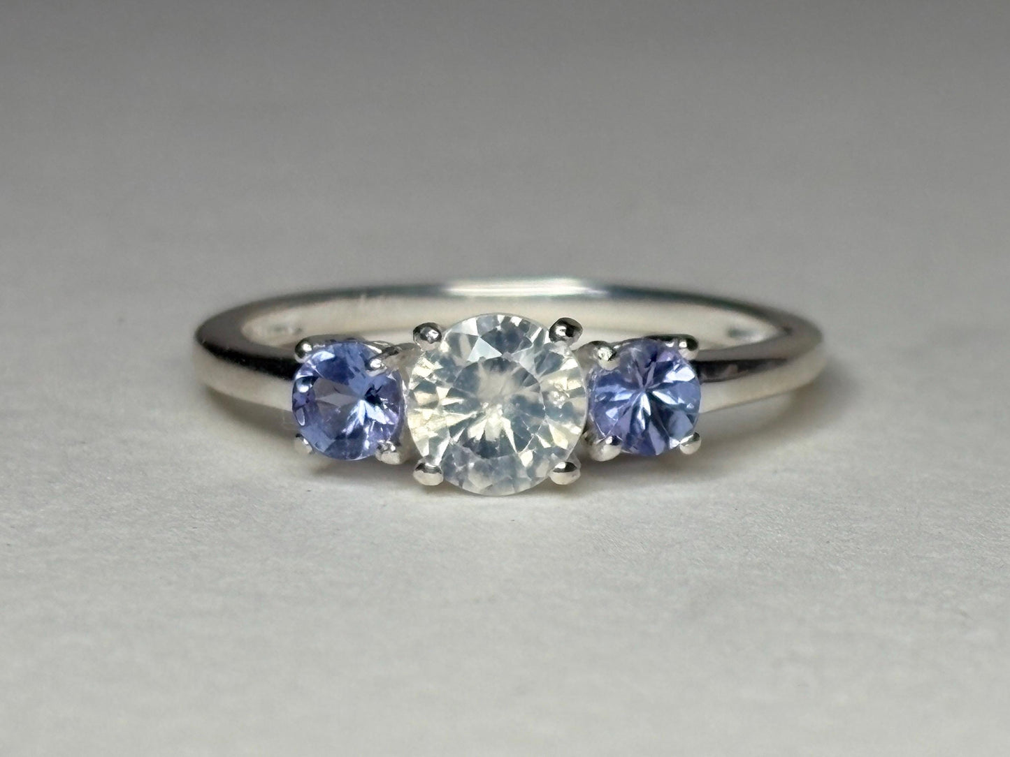 Sterling silver ring with a central off-white zircon and two tanzanite stones.