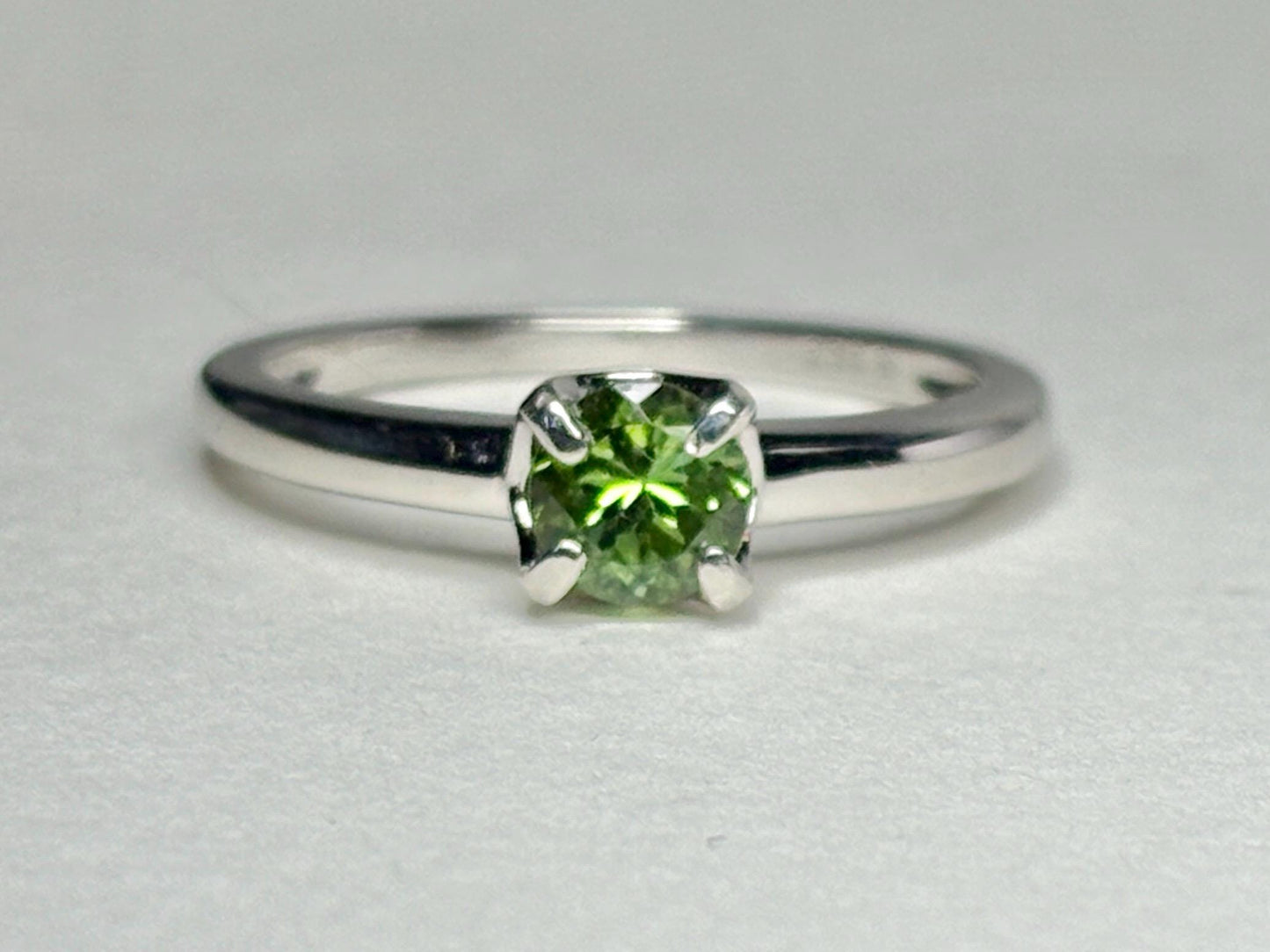 Sterling silver ring with a round, green tourmaline gemstone.