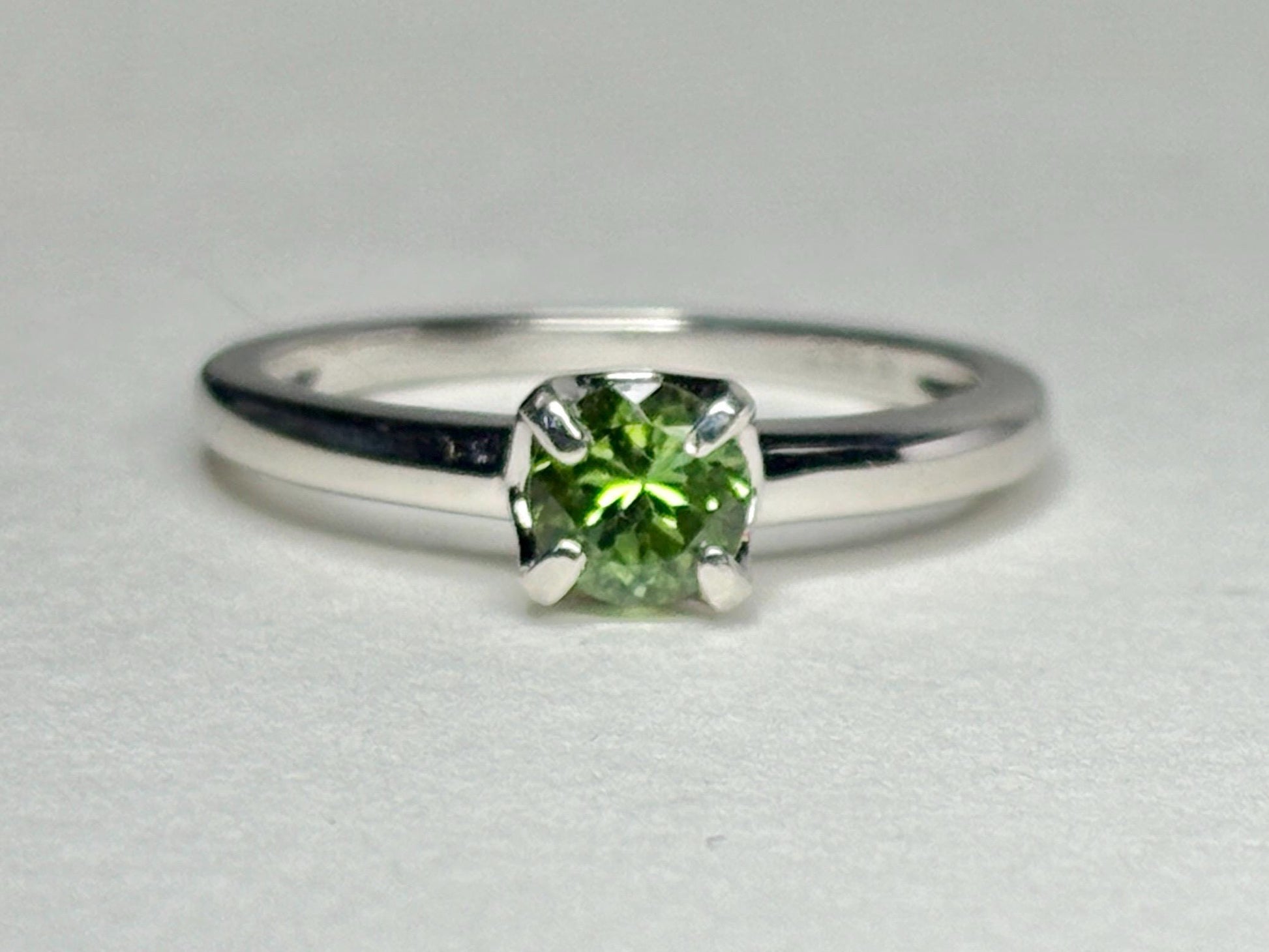 Sterling silver ring with a round, green tourmaline gemstone.