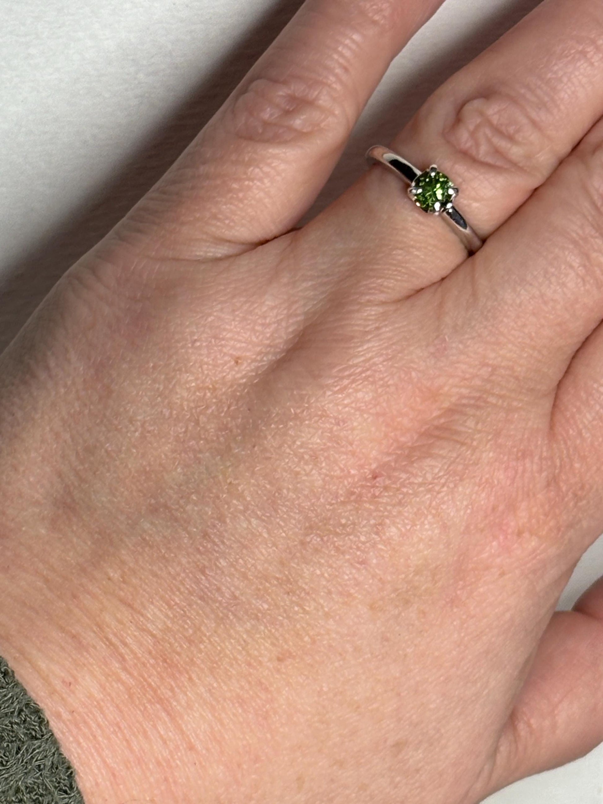 Sterling silver ring with a round, green tourmaline gemstone.