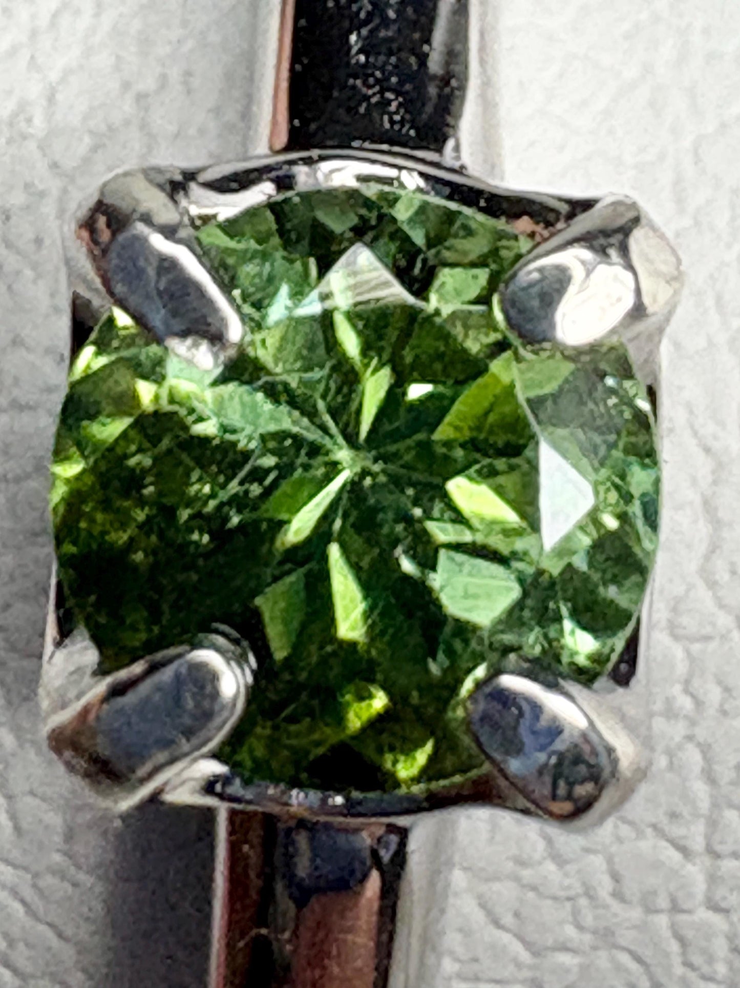 Sterling silver ring with a round, green tourmaline gemstone.