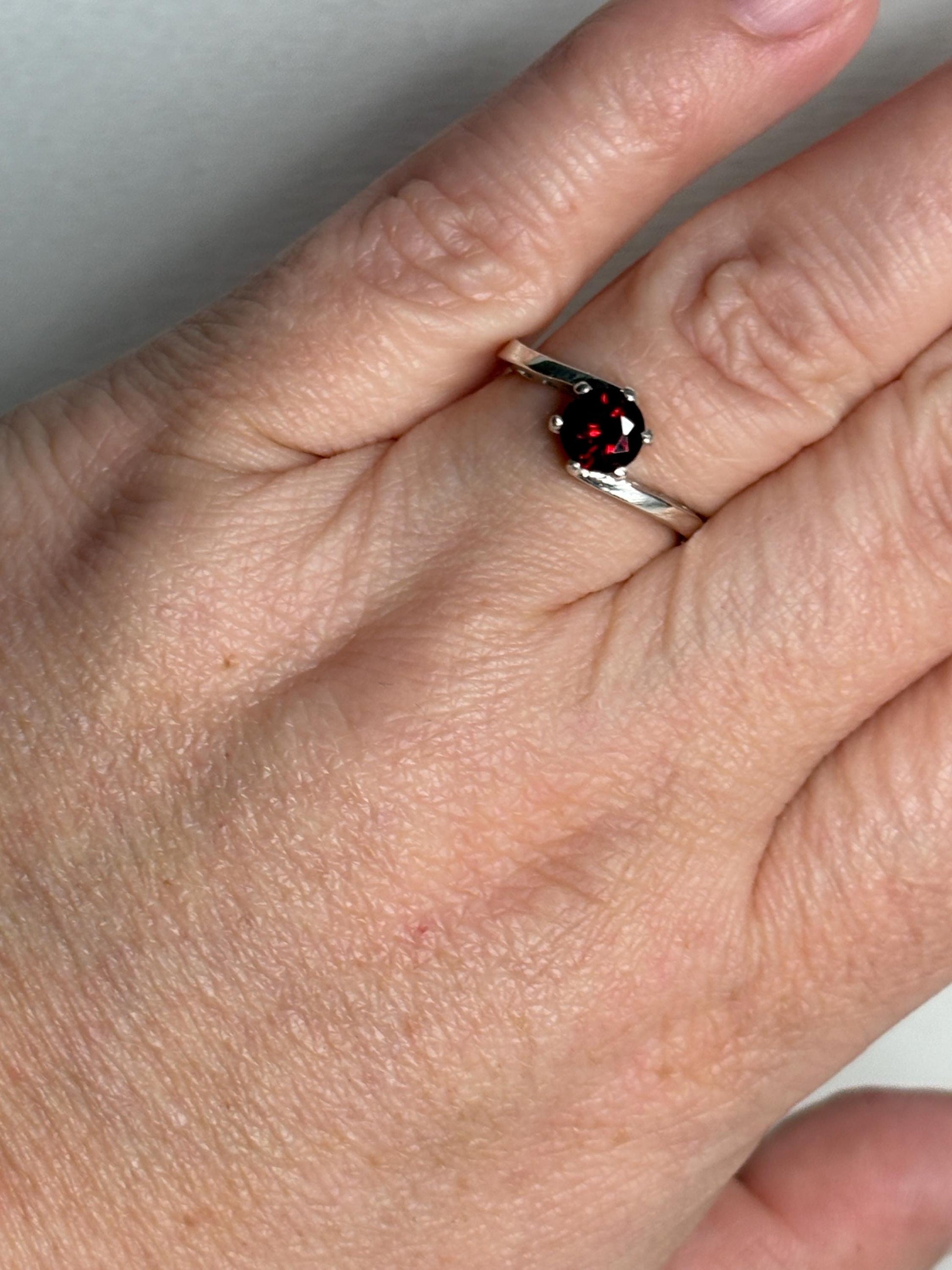Sterling silver bypass ring with a round pyrope garnet.