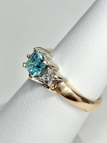 14k gold ring with a blue asscher cut tourmaline and two princess cut diamonds.