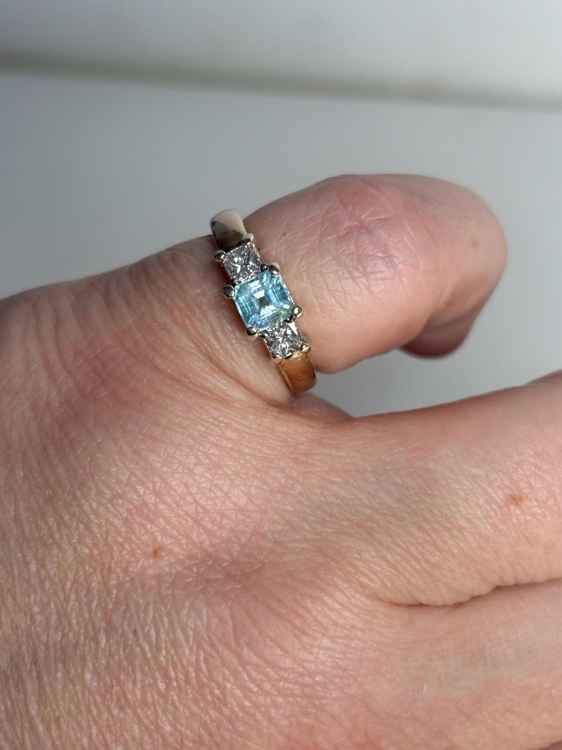 A 14k gold ring with a blue asscher cut tourmaline and two princess cut diamonds.