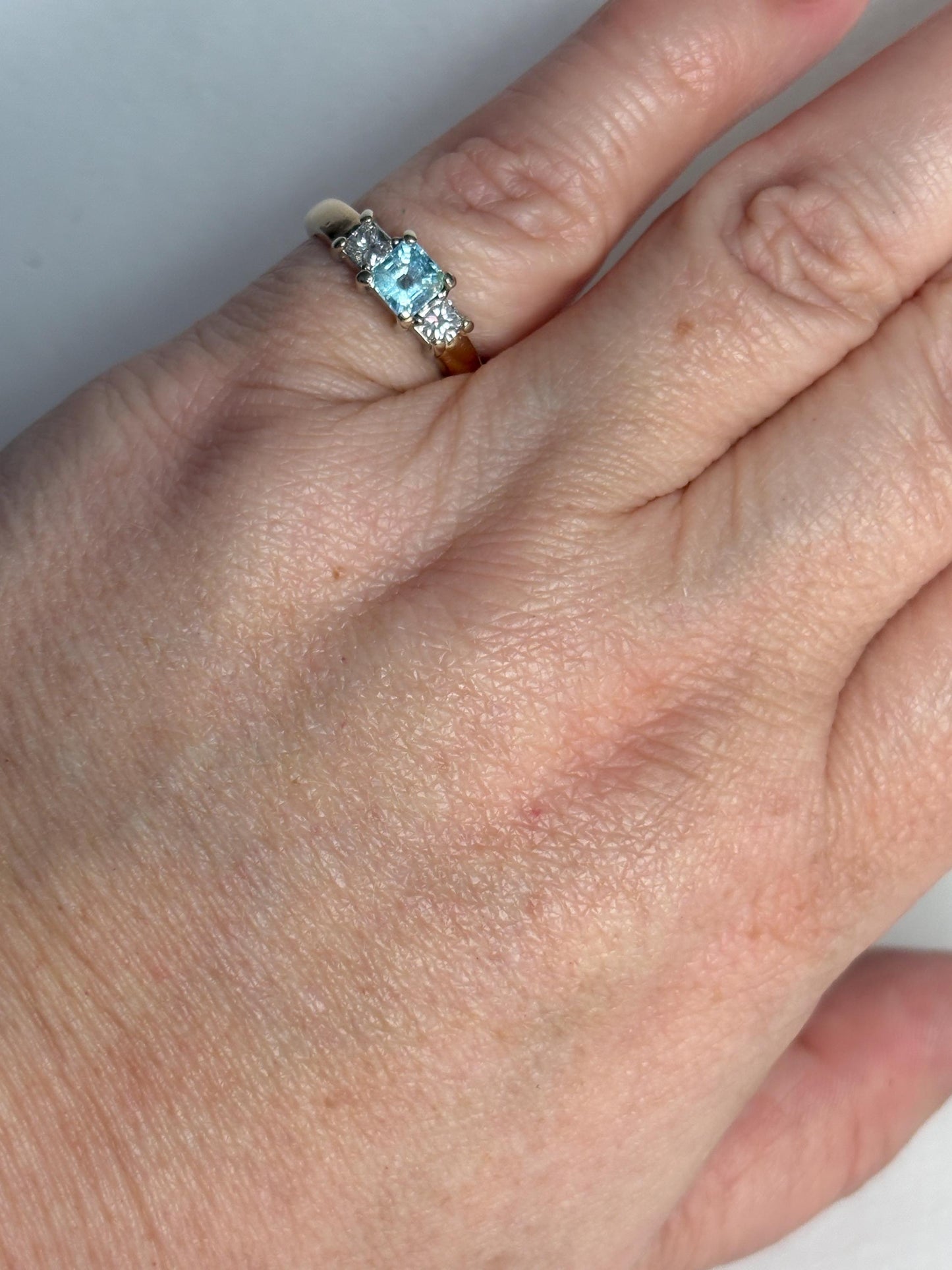 14k gold ring with a blue asscher cut tourmaline and two princess cut diamonds.