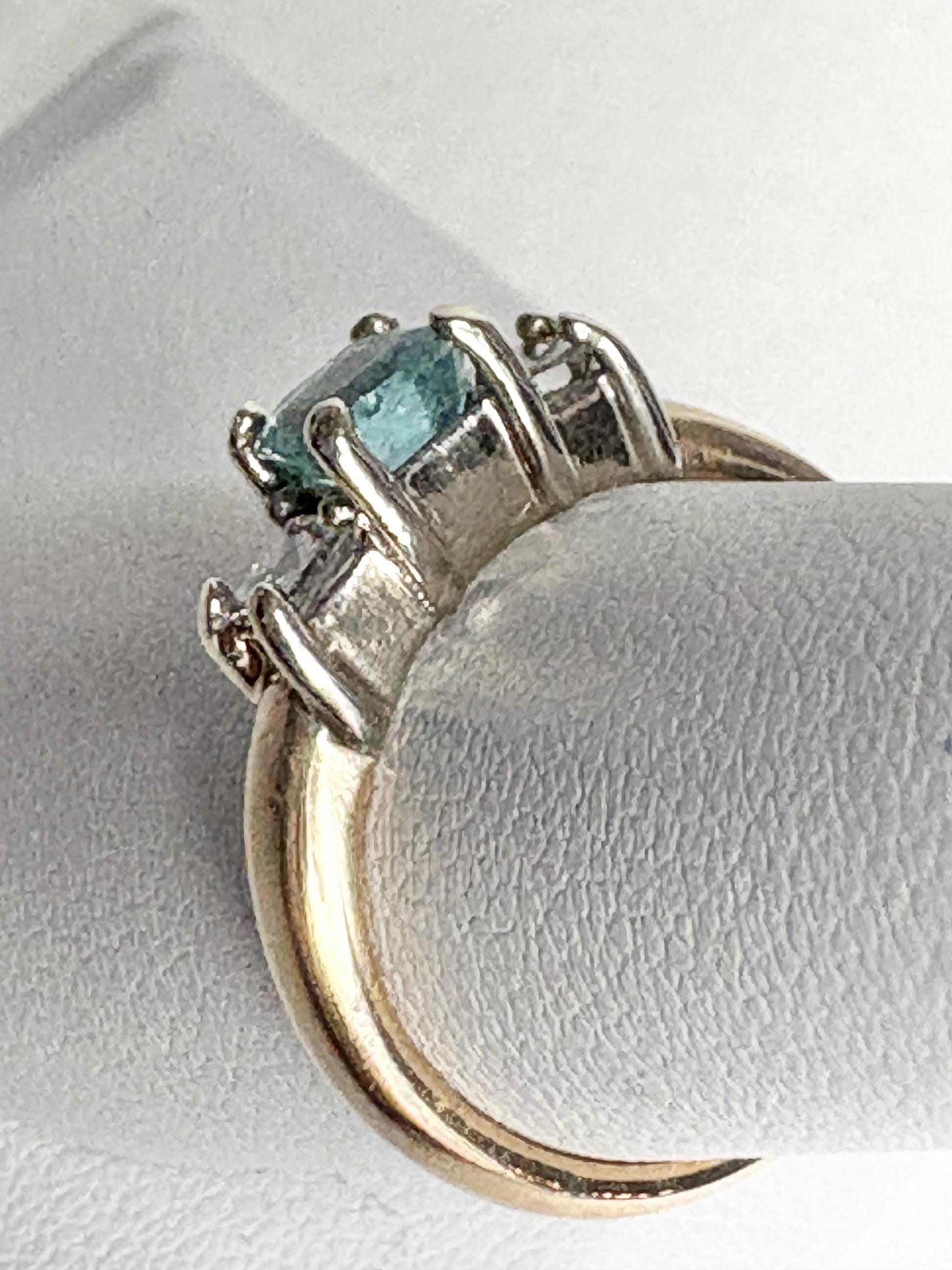 A 14k gold ring with a blue asscher cut tourmaline and two princess cut diamonds.
