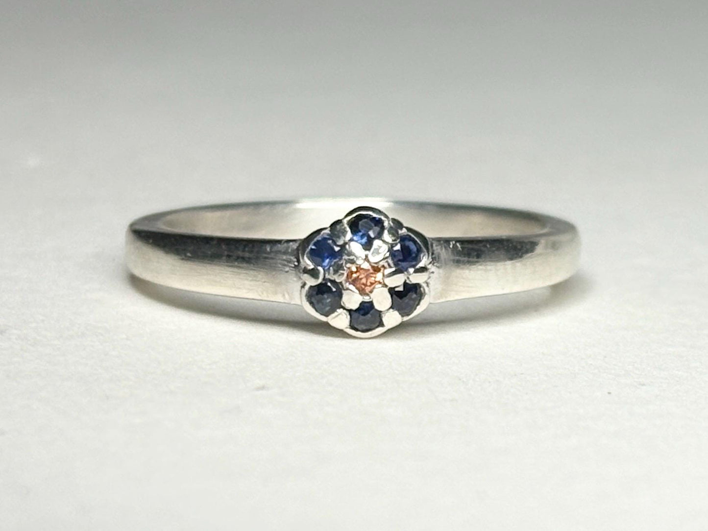 Sterling silver ring with a central gold sapphire and blue sapphire daisy halo.