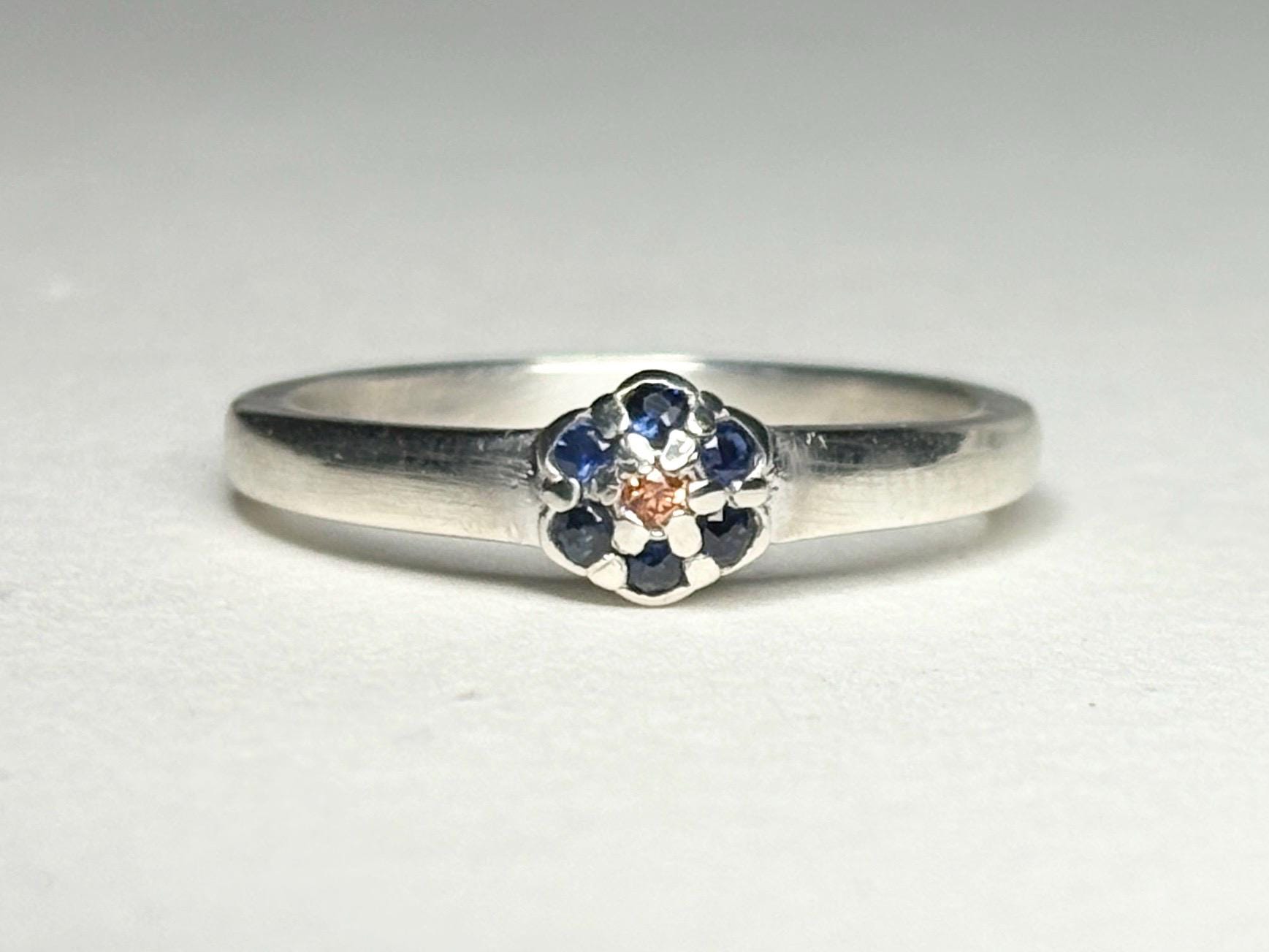 Sterling silver ring with a central gold sapphire and blue sapphire daisy halo.