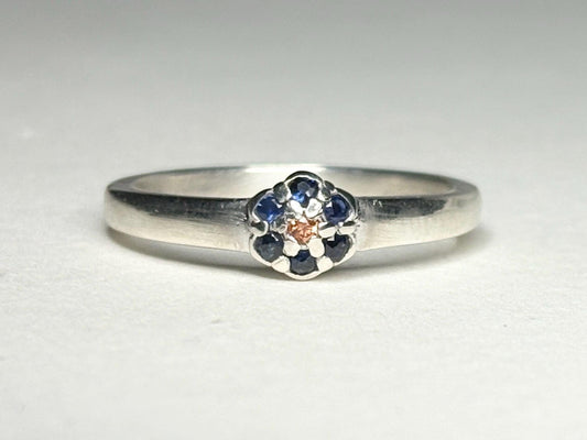 Sterling silver ring with a central gold sapphire and blue sapphire daisy halo.