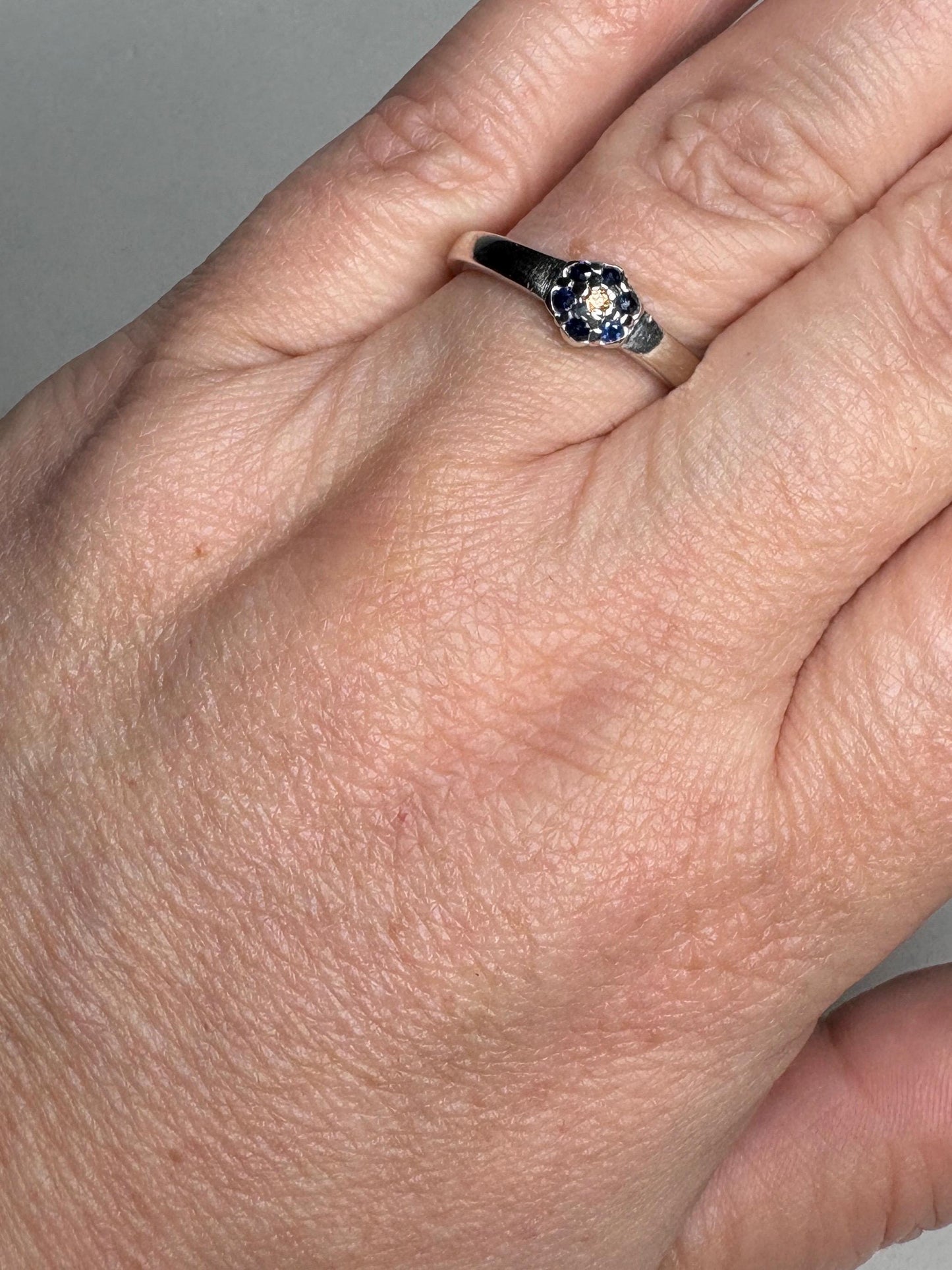Sterling silver ring with a central gold sapphire and blue sapphire daisy halo.