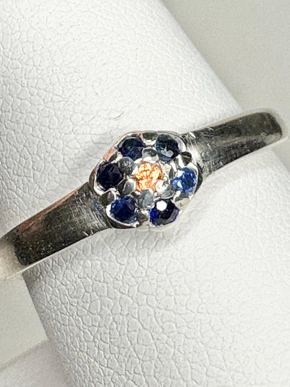 Sterling silver ring with a central gold sapphire and blue sapphire halo.