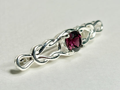 Sterling silver brooch with a Celtic knot design and a rhodolite garnet.