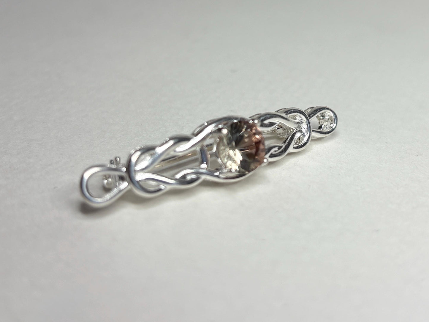 Sterling silver brooch with a Celtic knot design and a light peach Oregon sunstone.