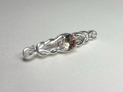Sterling silver brooch with a Celtic knot design and a light peach Oregon sunstone.