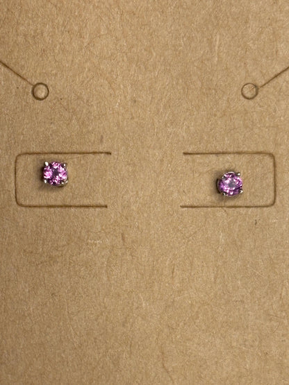 Two small, square-set rhodolite garnet stud earrings with silver settings on a brown background.