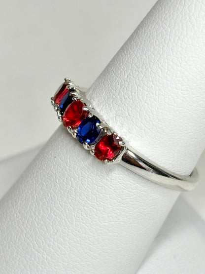 Sterling silver band ring with alternating oval red and blue sapphires.
