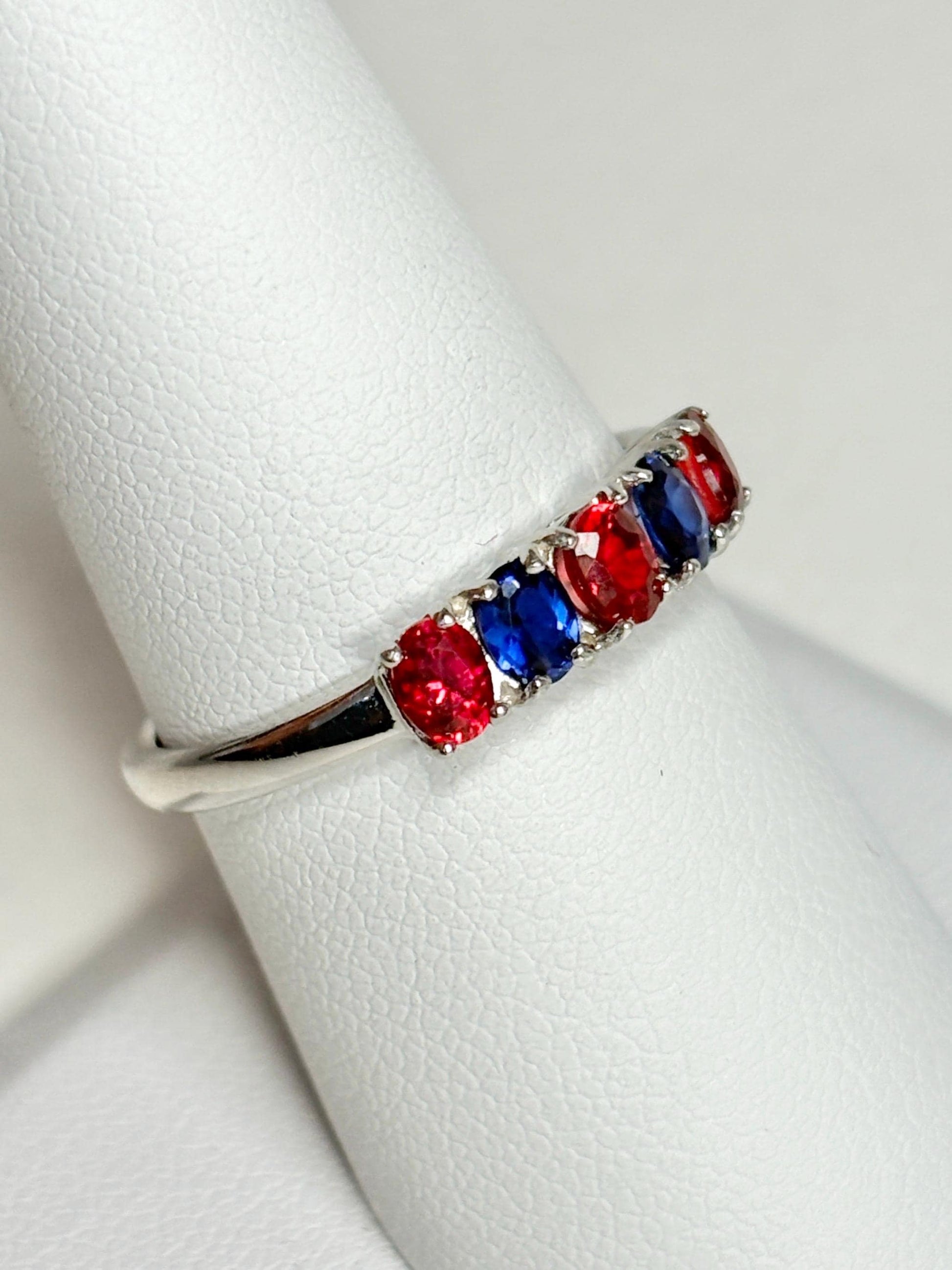 Sterling silver band ring with alternating oval red and blue sapphires.