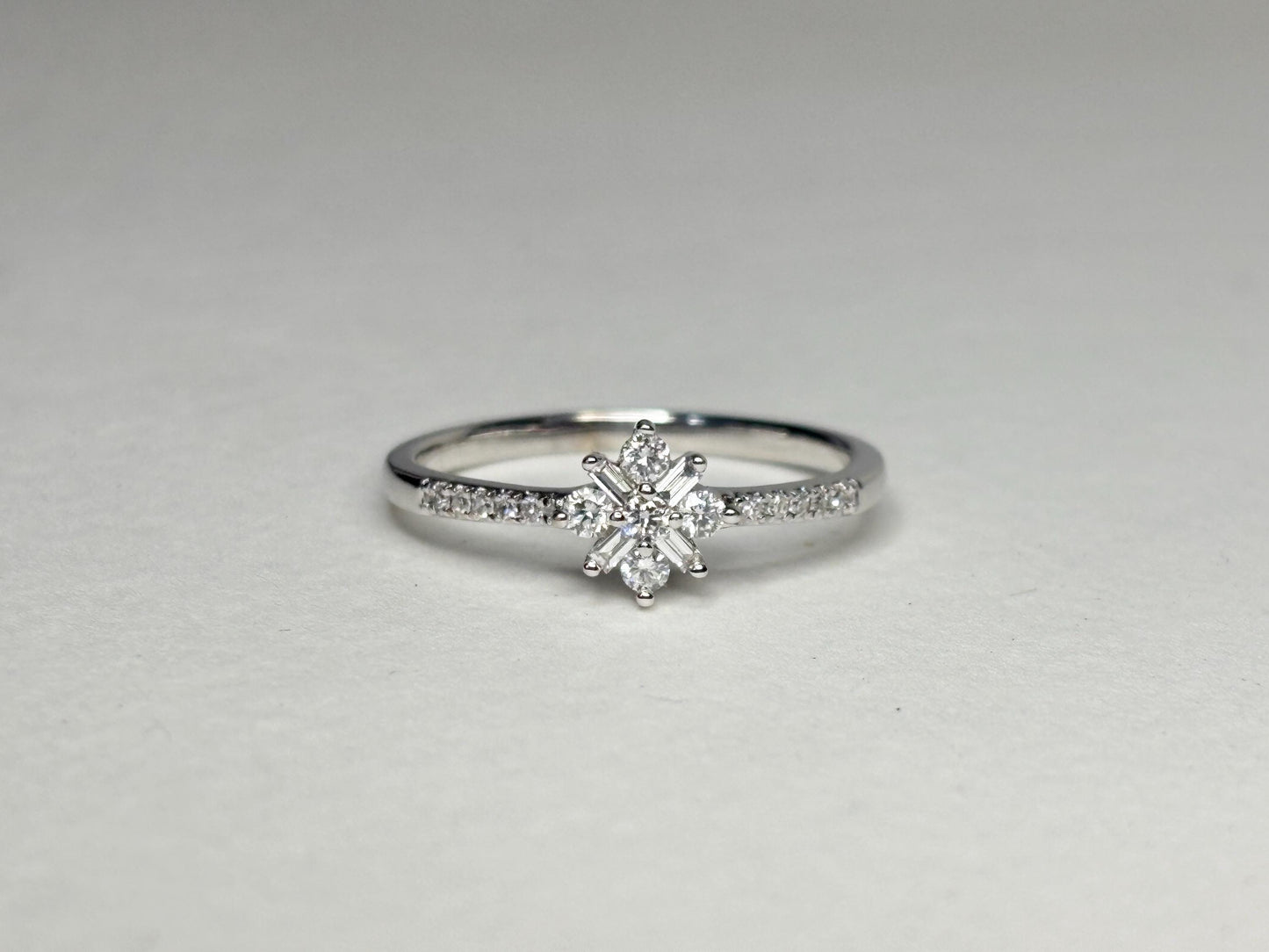 A white gold ring with a starburst design of baguette and round diamonds.