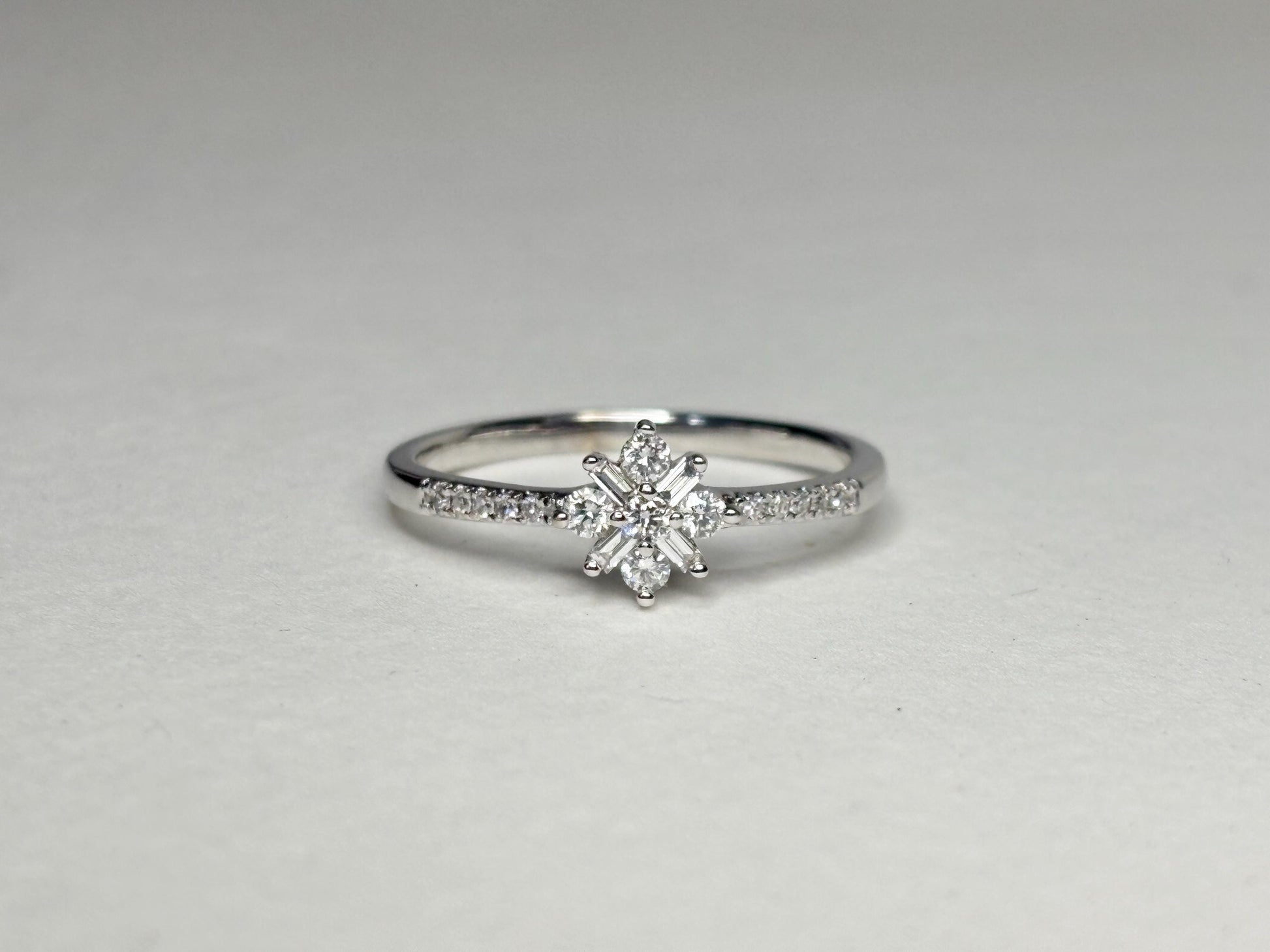 A white gold ring with a starburst design of baguette and round diamonds.