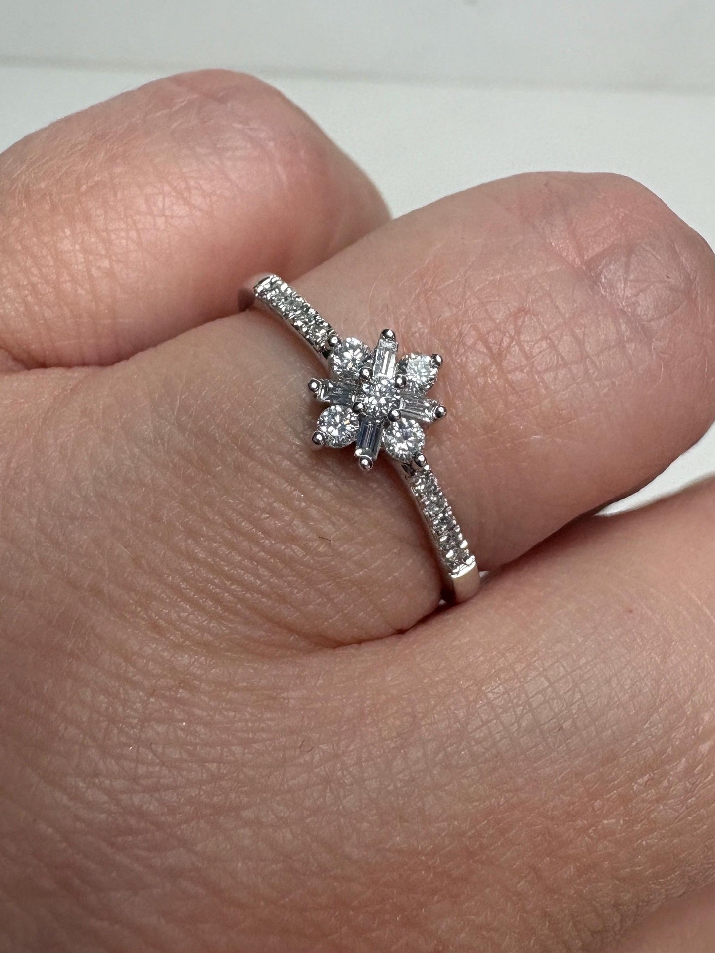 A white gold ring with a starburst design of baguette and round diamonds.