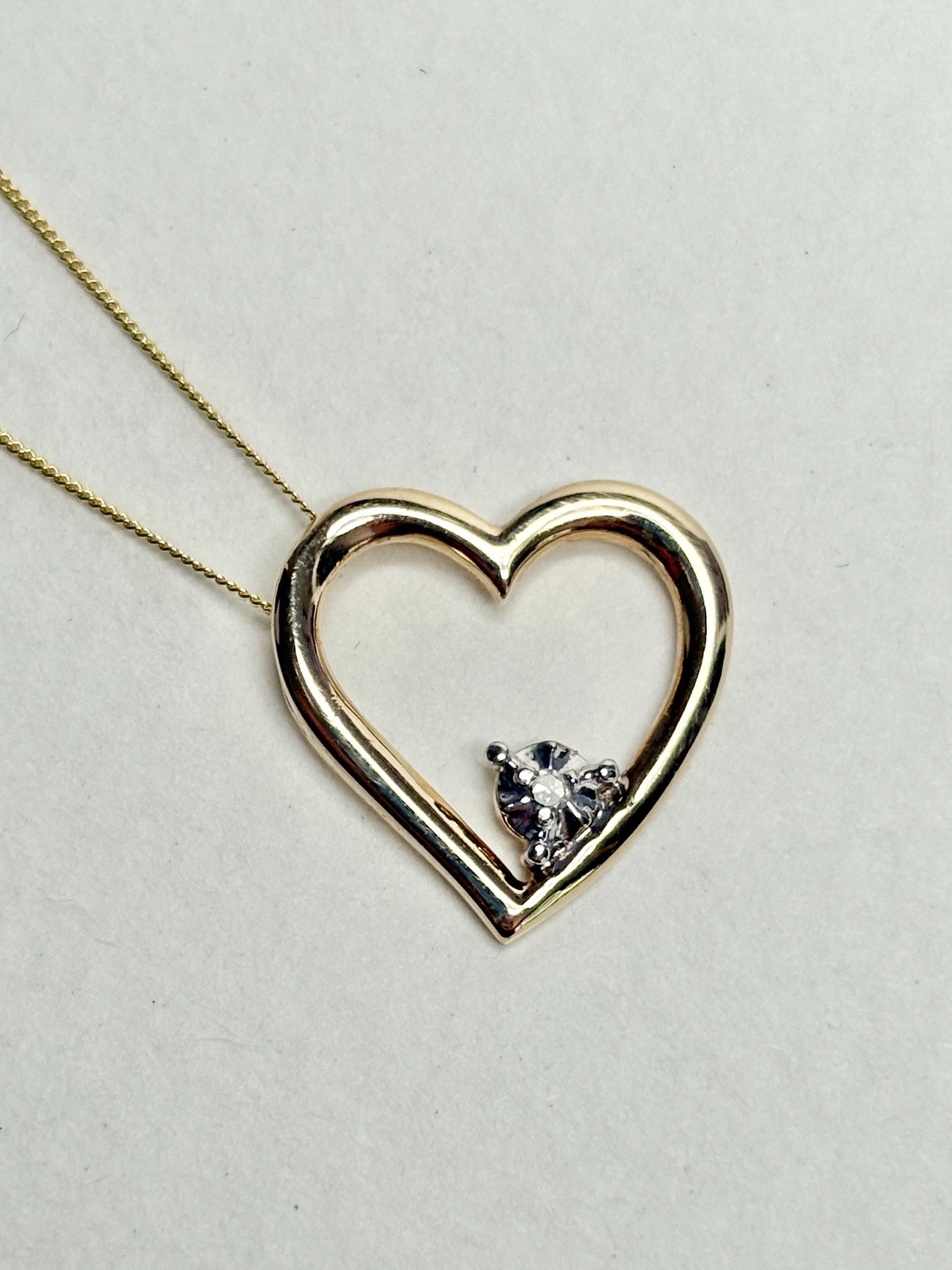 A gold heart pendant with a small diamond on an 18-inch gold chain.