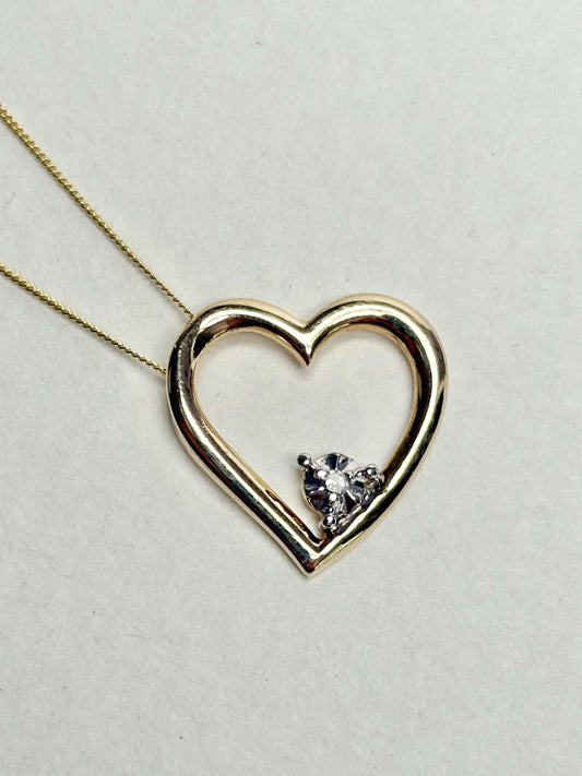 A gold heart pendant with a small diamond on an 18-inch gold chain.