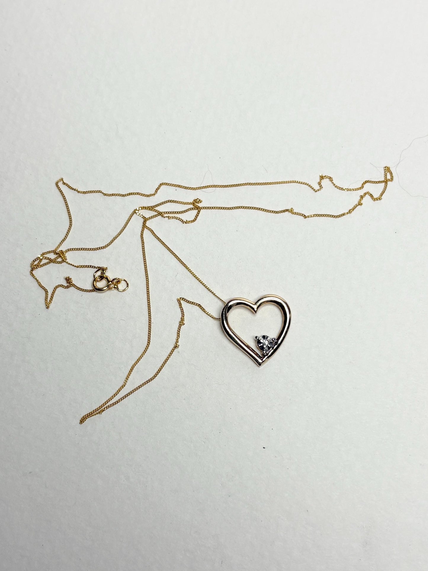 A gold heart pendant with a diamond chip on an 18-inch gold chain.
