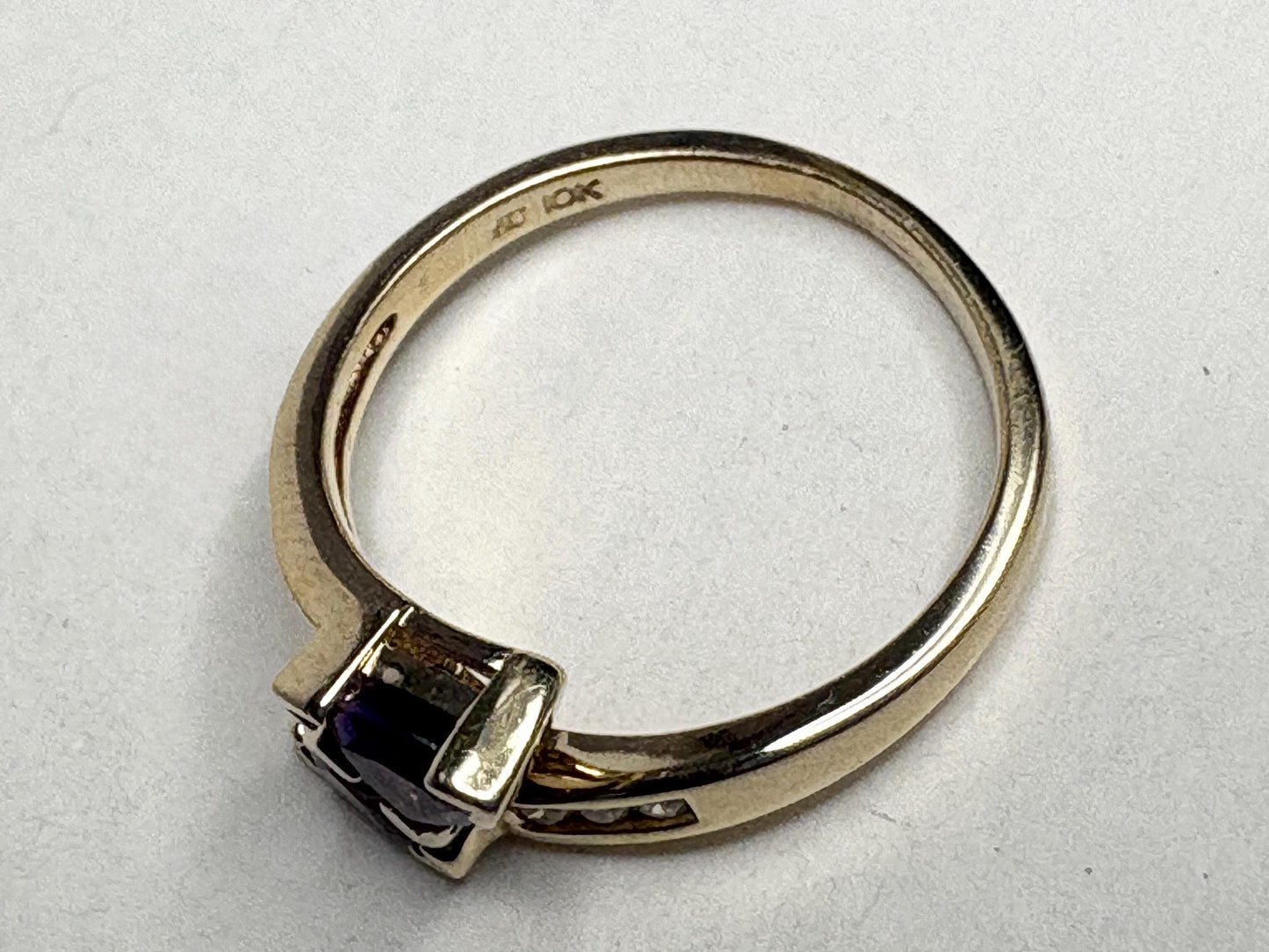 A 10k yellow gold ring with a trillion amethyst and channel-set diamonds.