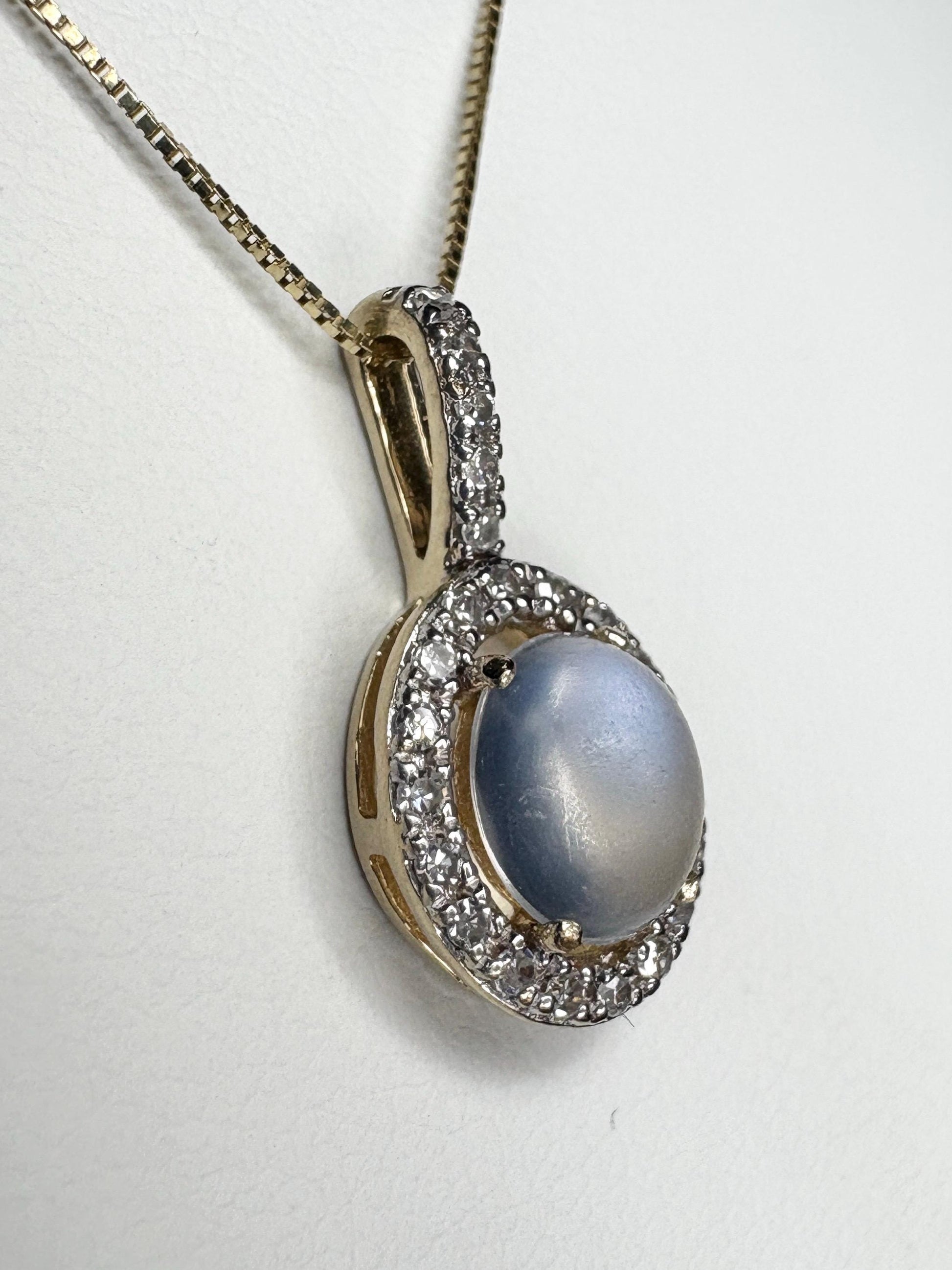 Gold pendant necklace with a blue moonstone and diamond halo.
