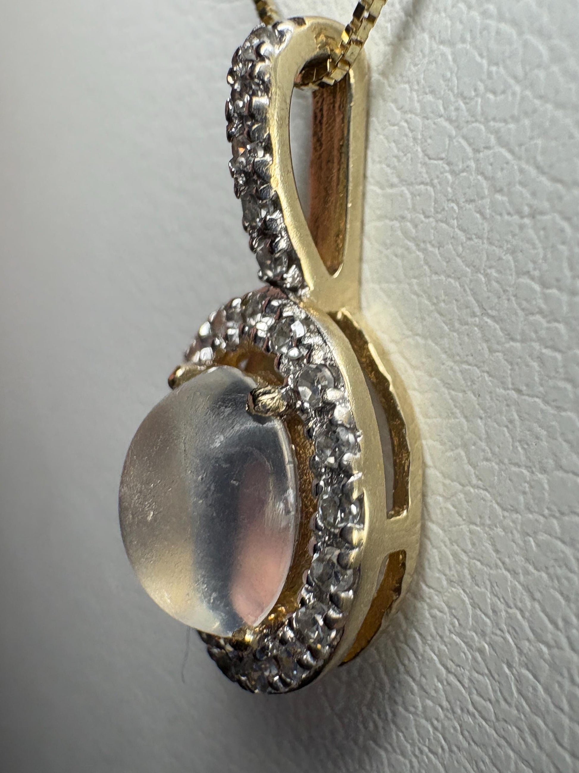 A blue sheen moonstone pendant with a diamond halo in 10k gold.