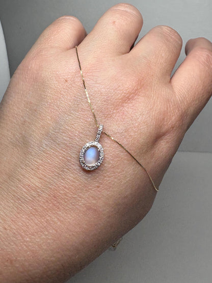 Oval blue sheen moonstone pendant necklace with diamond halo in 10k gold.