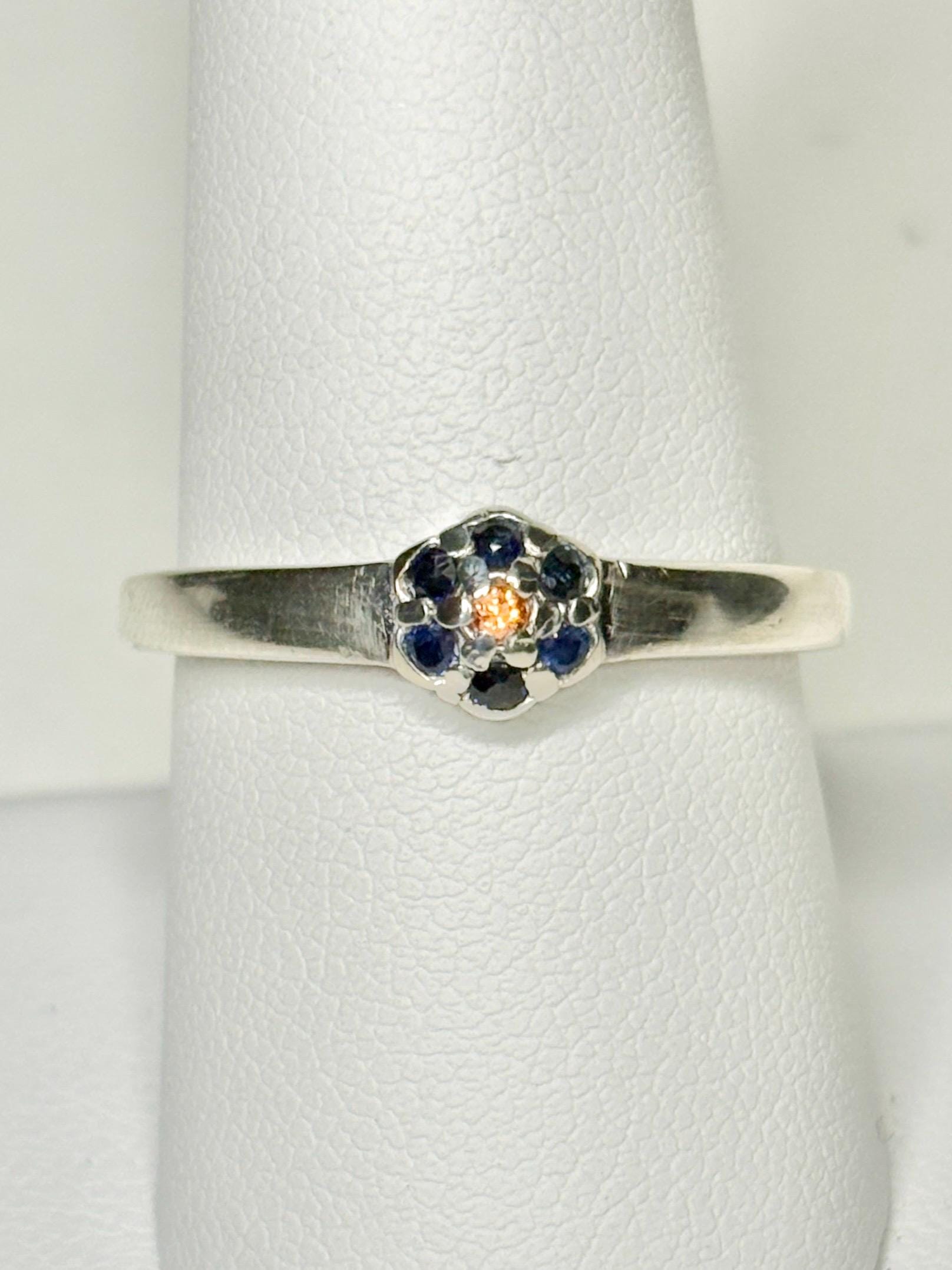 Sterling silver ring with a central gold sapphire surrounded by blue sapphires in a daisy halo design.