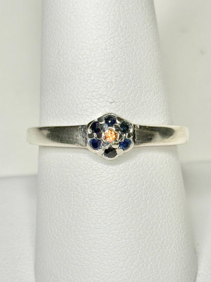 Sterling silver ring with a central gold sapphire surrounded by blue sapphires in a daisy halo design.