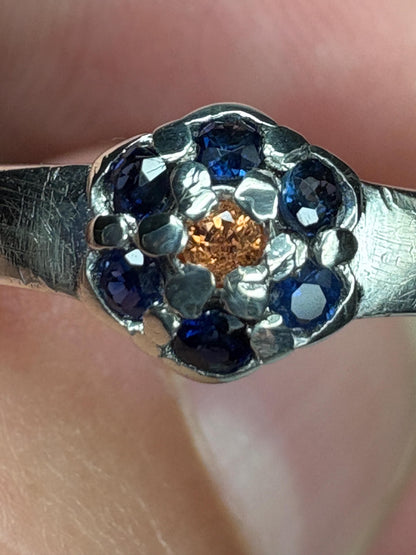 Sterling silver ring with a gold sapphire center and blue sapphire halo.