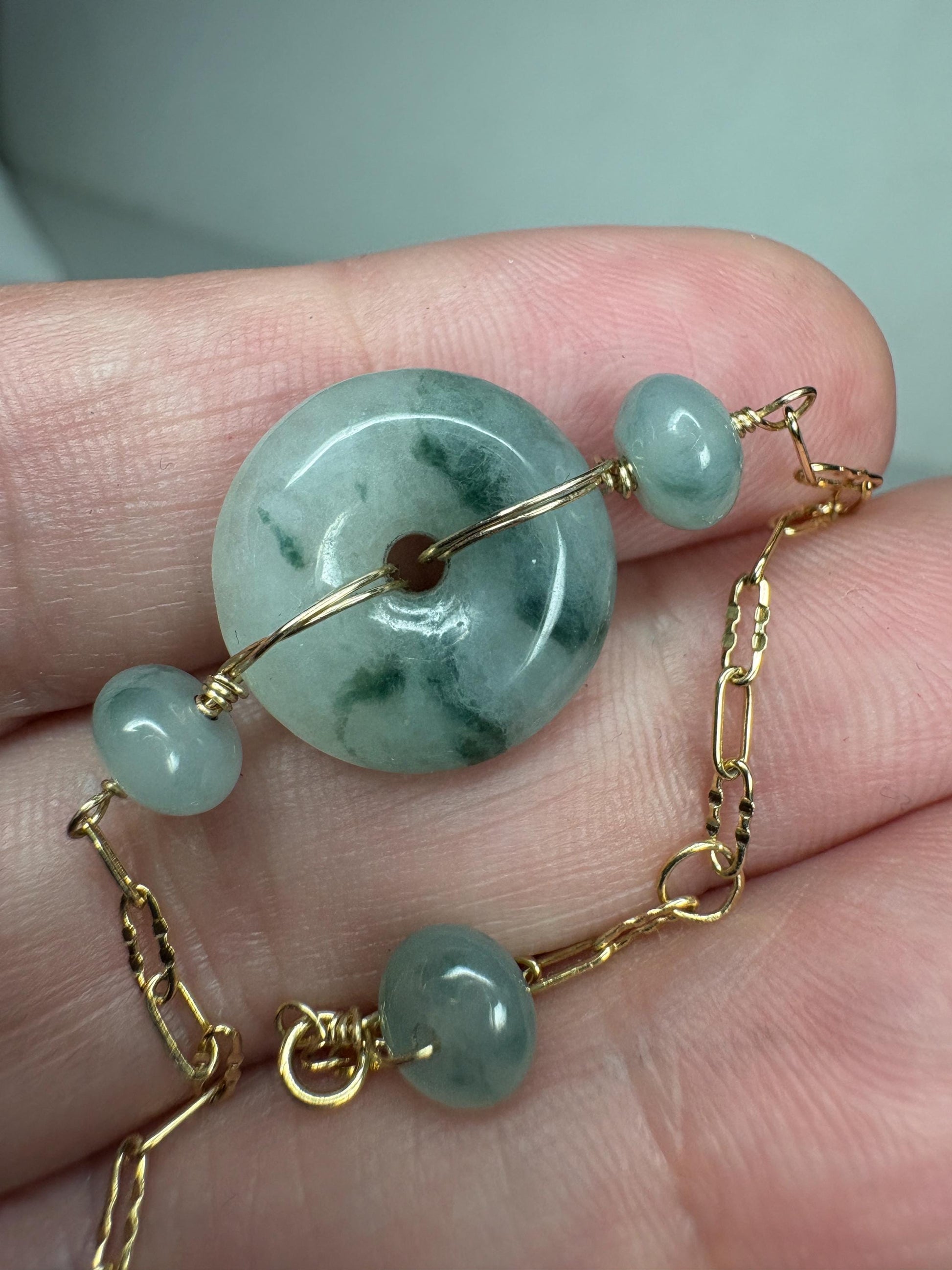 A 14k gold bracelet with a Type A Burmese jadeite Pi donut and smaller jade beads.