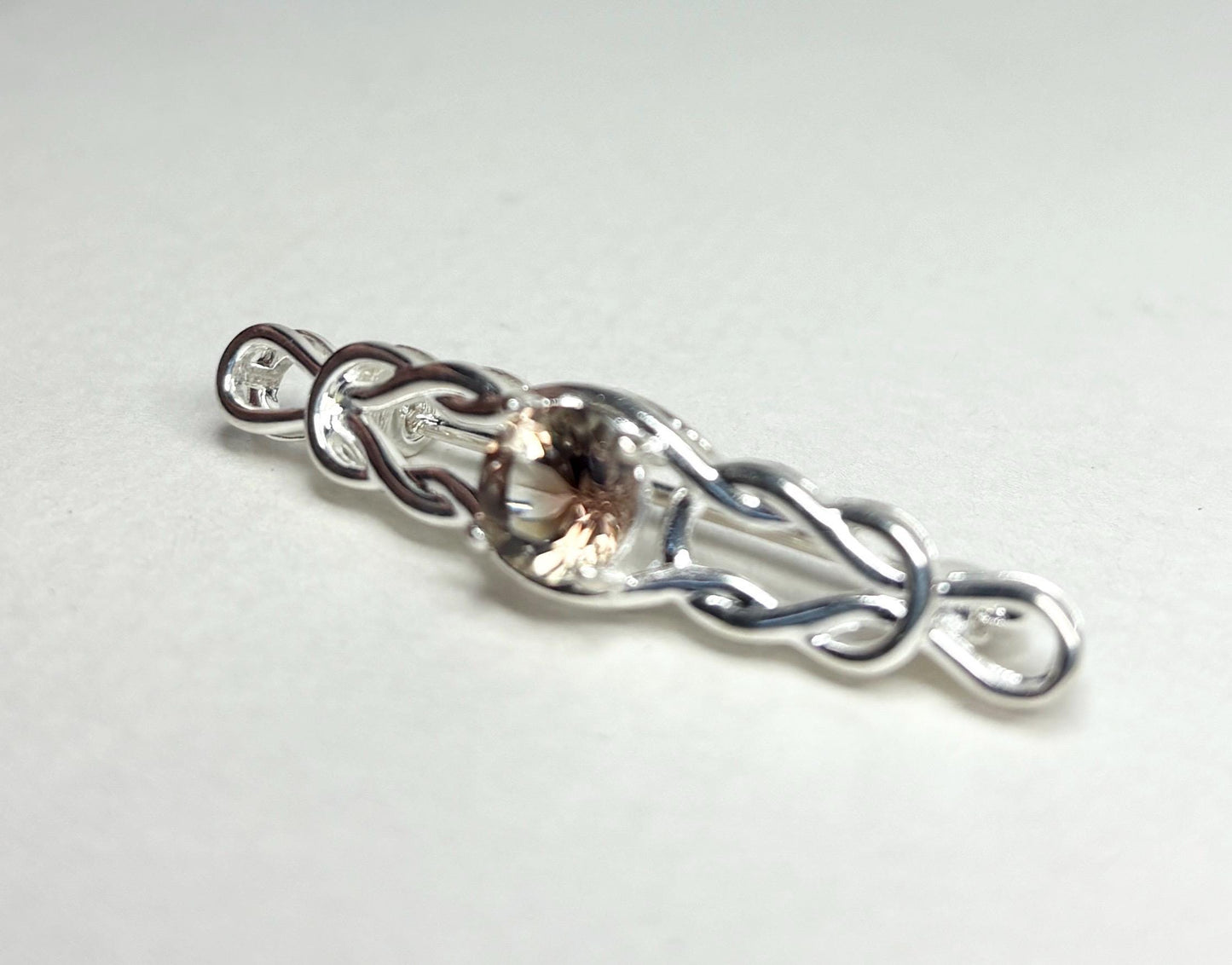 Sterling silver brooch with a Celtic knot design and a light peach Oregon sunstone.