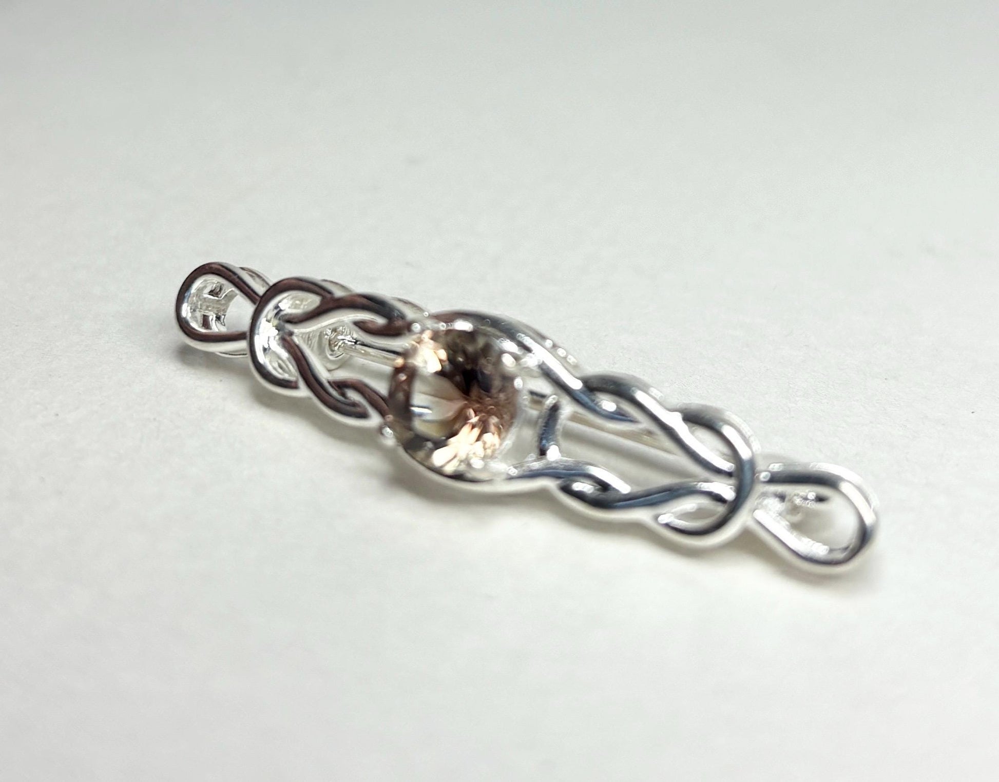 Sterling silver brooch with a Celtic knot design and a light peach Oregon sunstone.