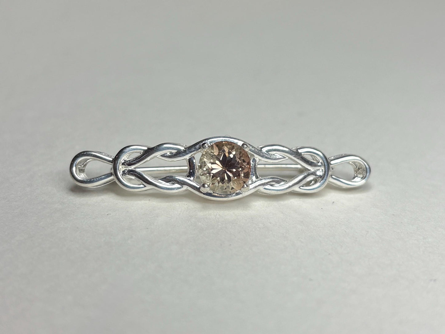 Sterling silver bar brooch with a Celtic knot design and a round light peach Oregon sunstone.