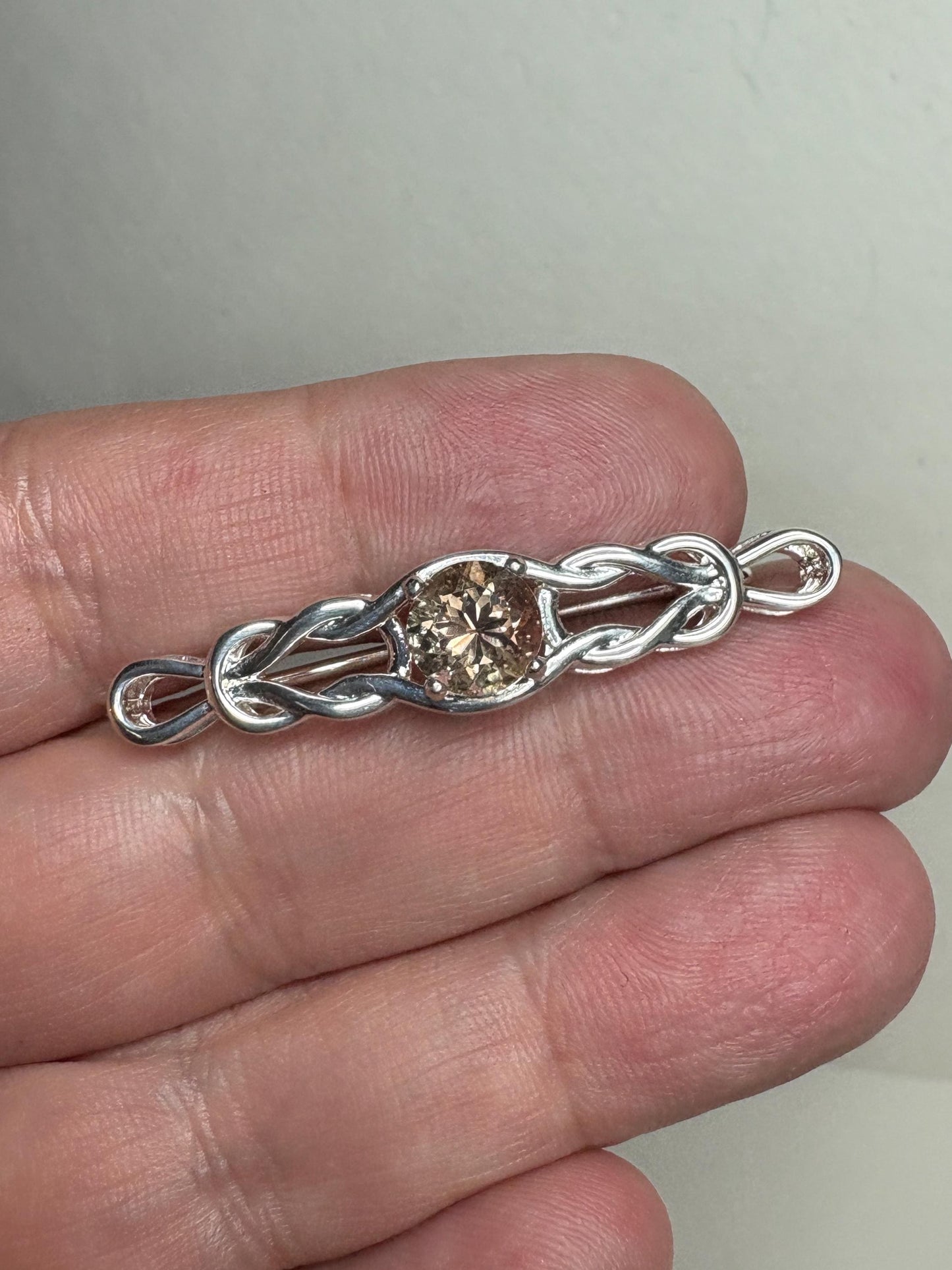 Sterling silver brooch with a light peach Oregon sunstone and Celtic knot design.