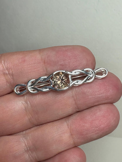 Sterling silver brooch with a light peach Oregon sunstone and Celtic knot design.
