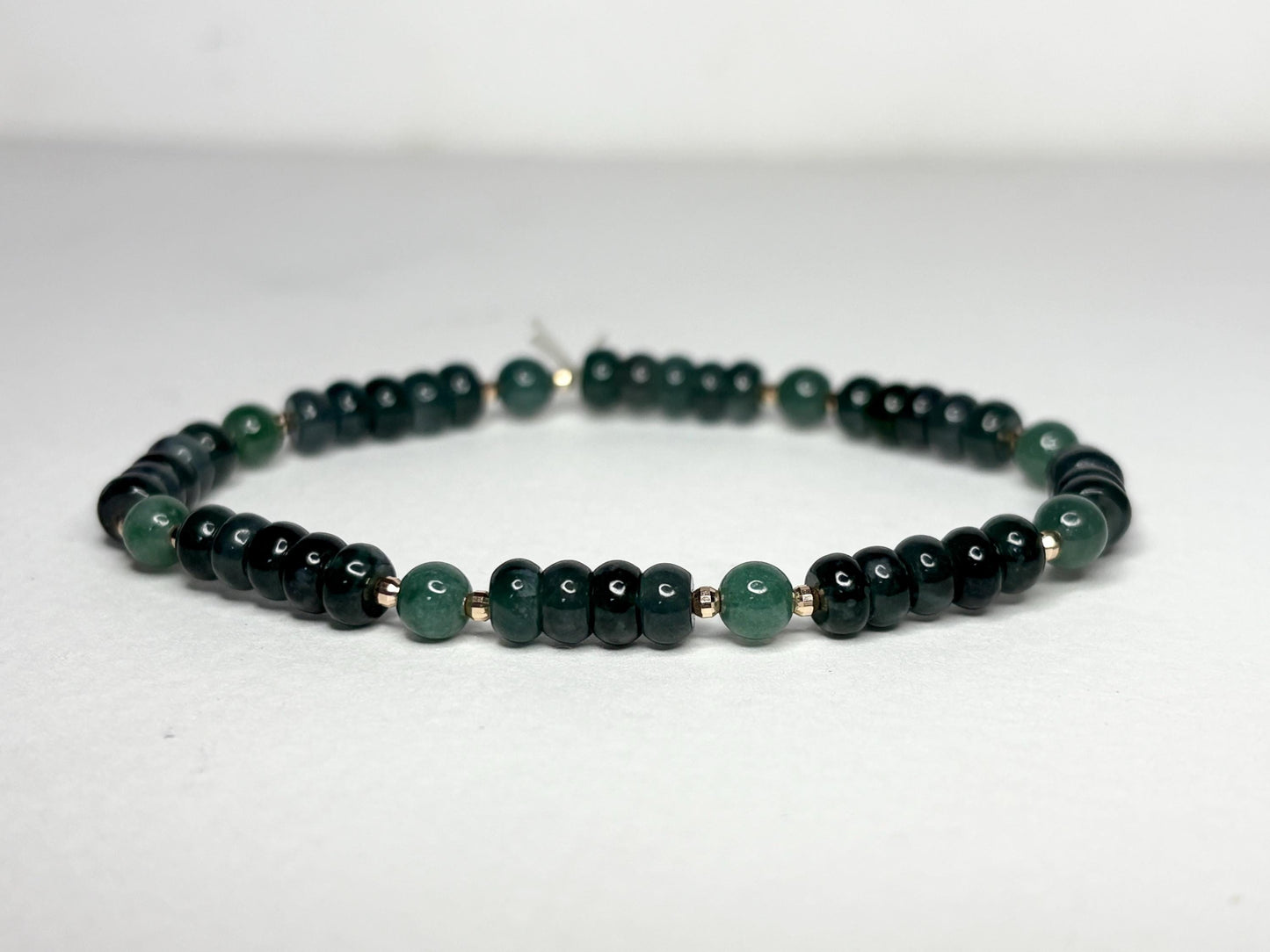A stretch bracelet with dark green jadeite beads and solid 14k gold beads.