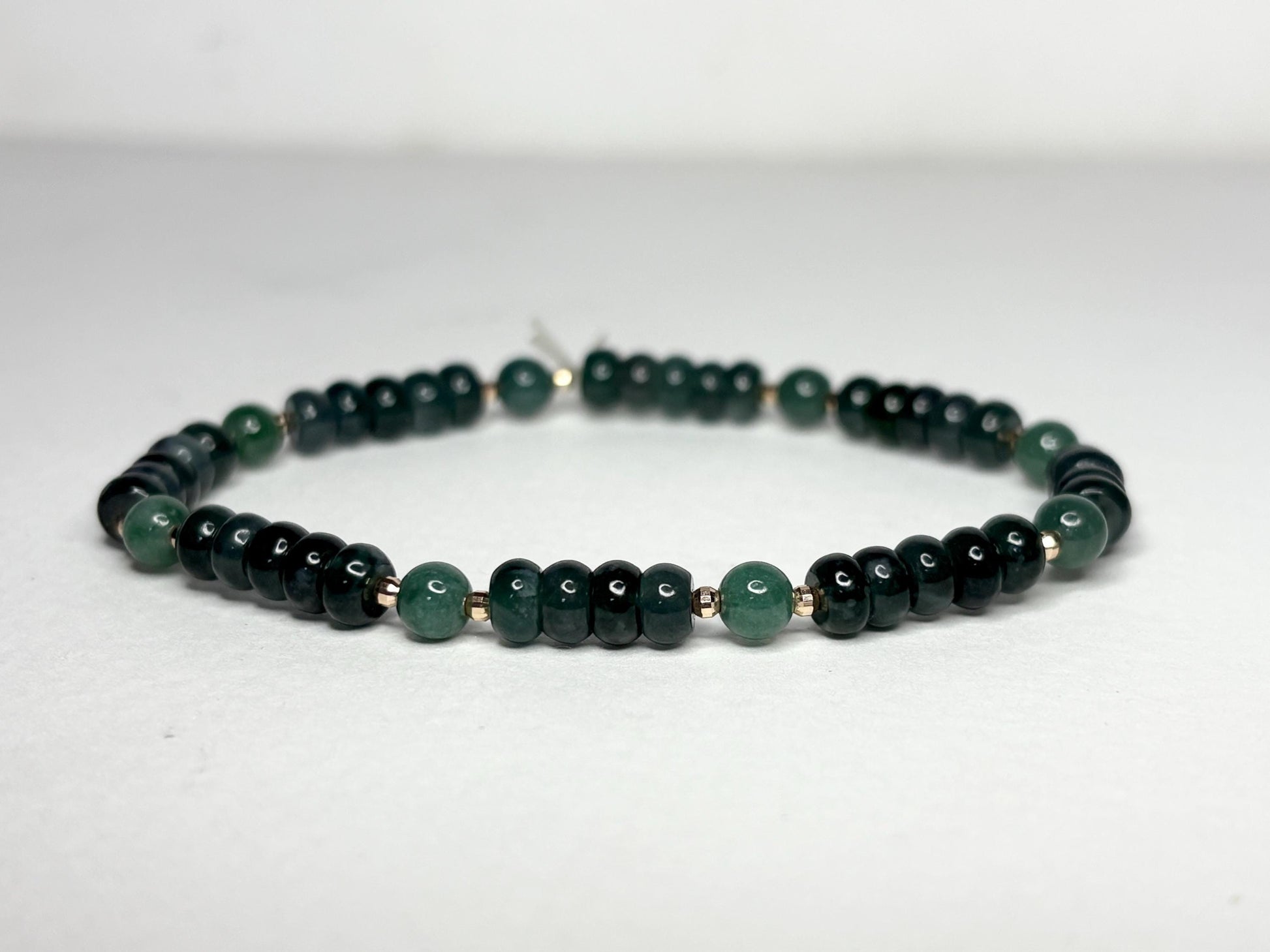 A stretch bracelet with dark green jadeite beads and solid 14k gold beads.