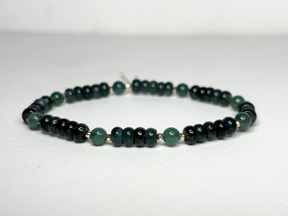 A stretch bracelet with dark green jadeite beads and solid 14k gold beads.